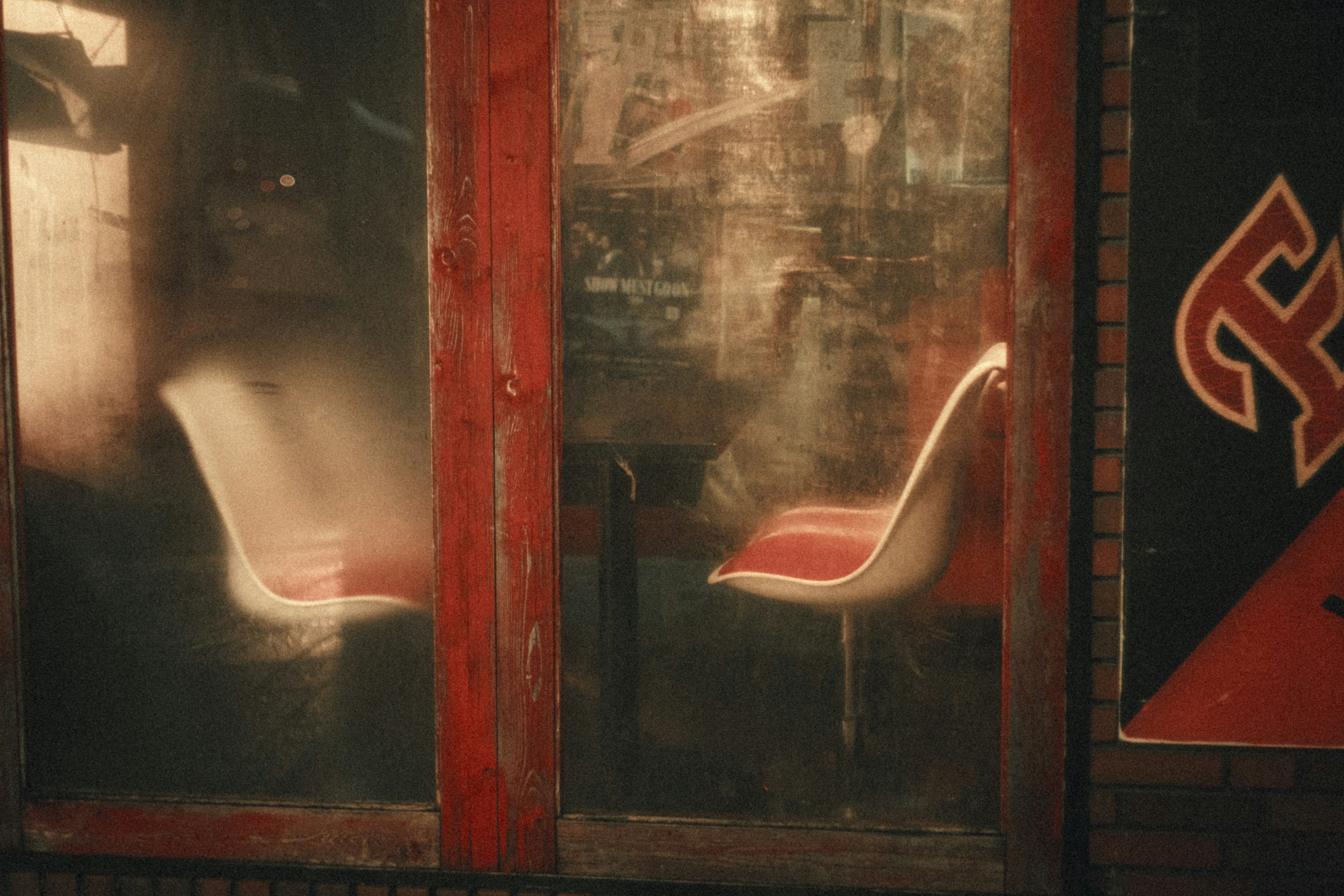 Chaises blanches avec des coussins rouges visibles à travers une fenêtre en verre embuée