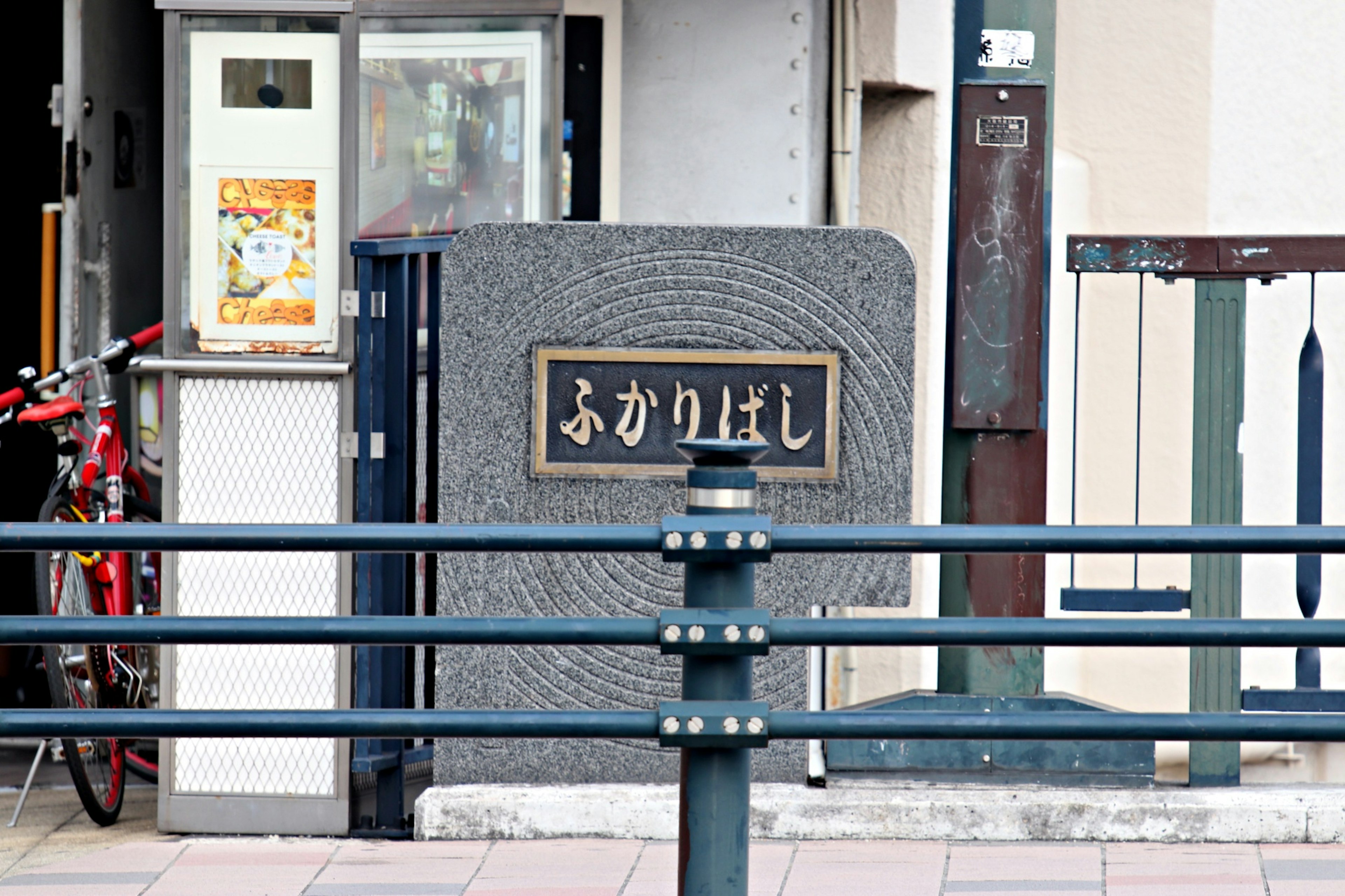 赤い自転車が置かれた石の門と看板のある通り