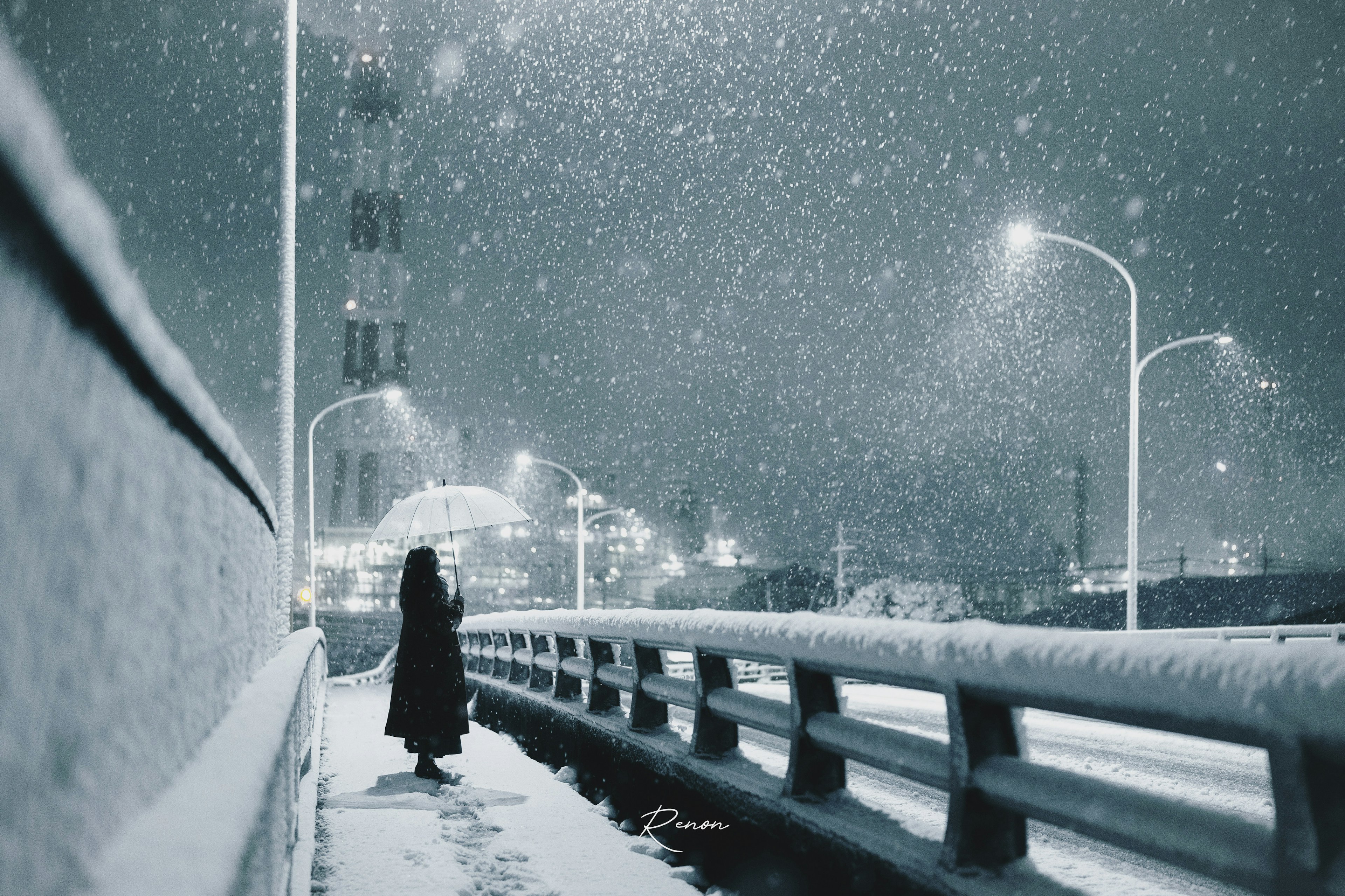 Una figura in un cappotto nero che cammina su un ponte innevato di notte