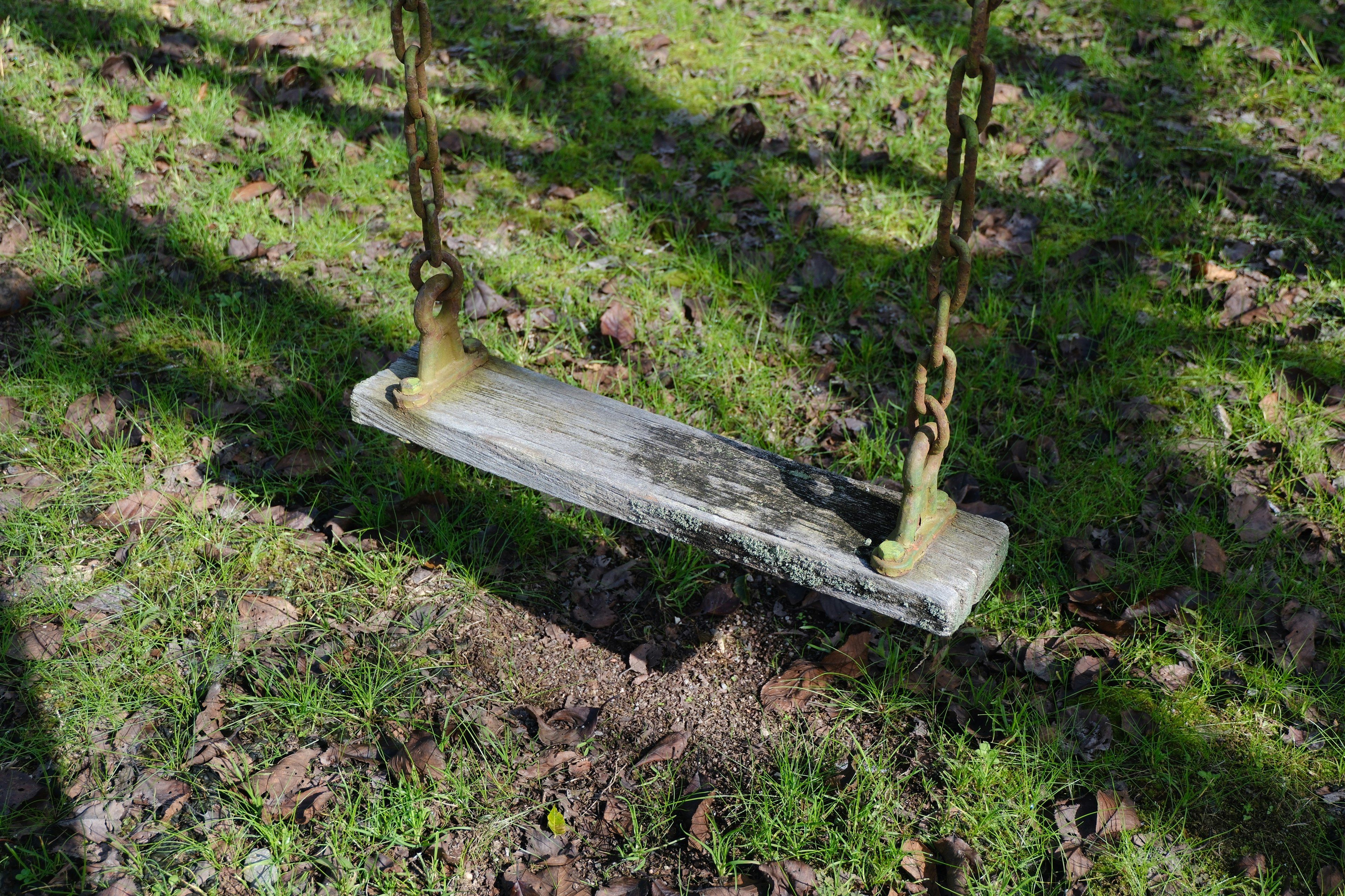 An old swing hanging on grass ground