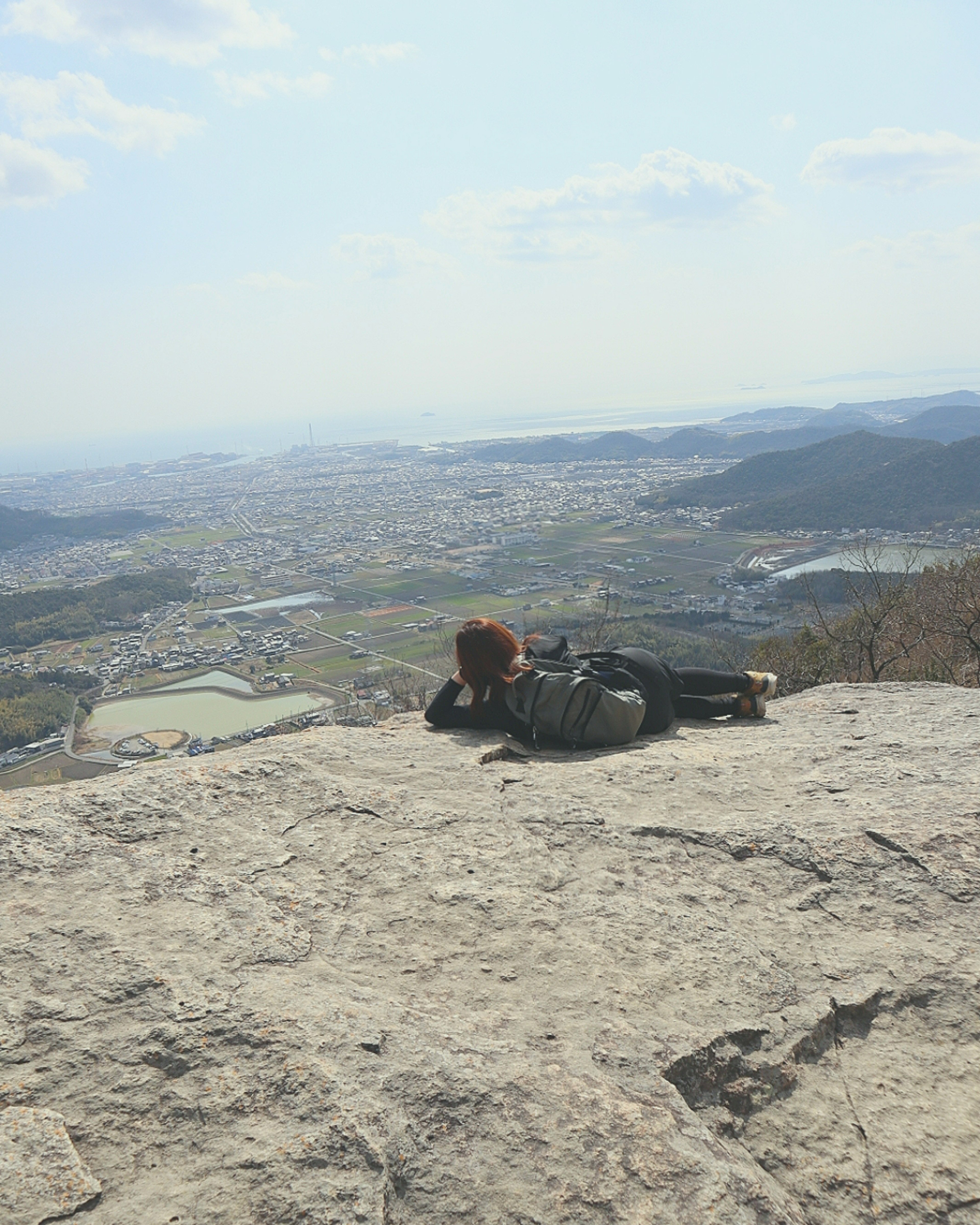 山の頂上で横たわる人物と広がる風景