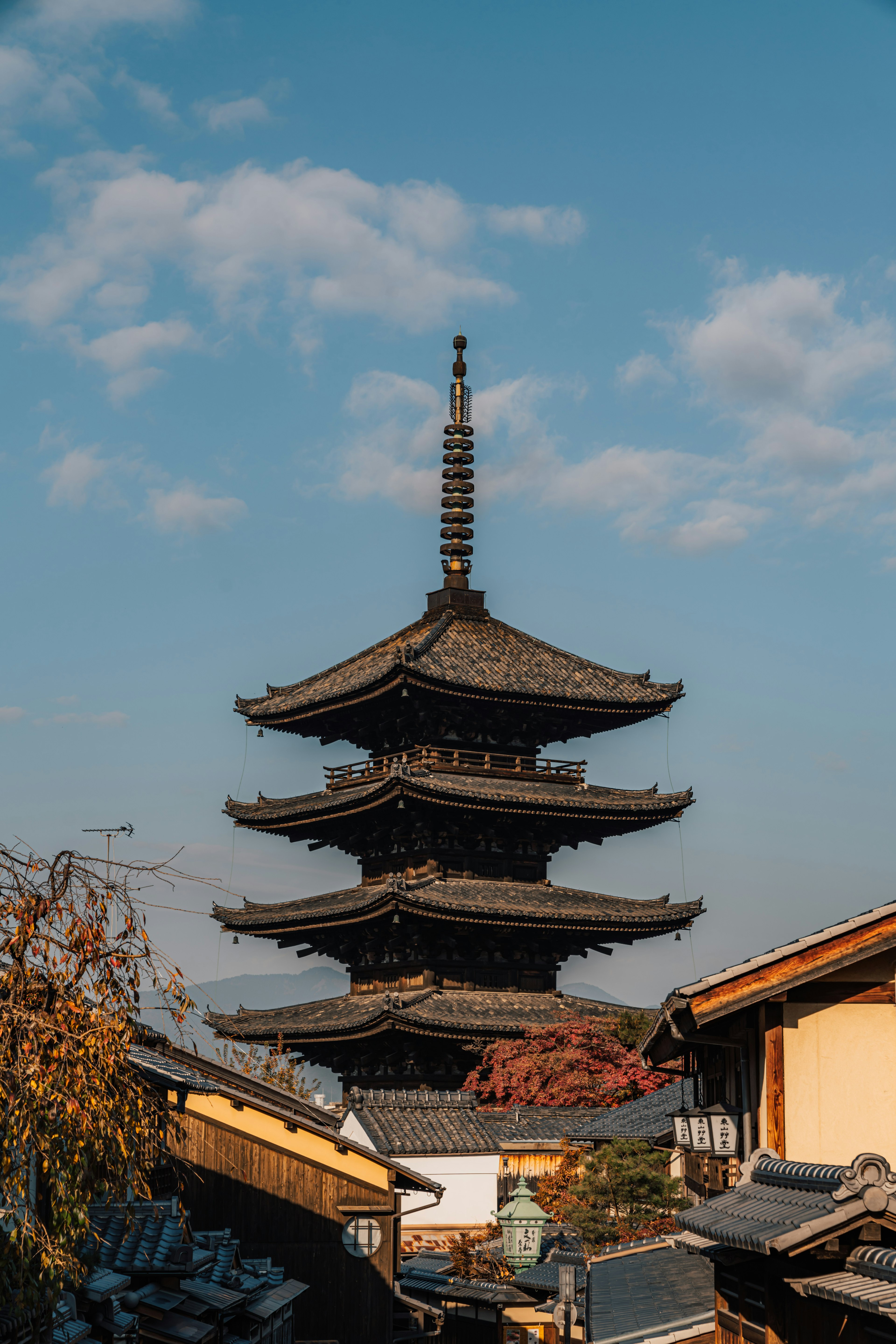 Fünfstöckige Pagode vor blauem Himmel mit herbstlicher Vegetation und traditionellen Gebäuden