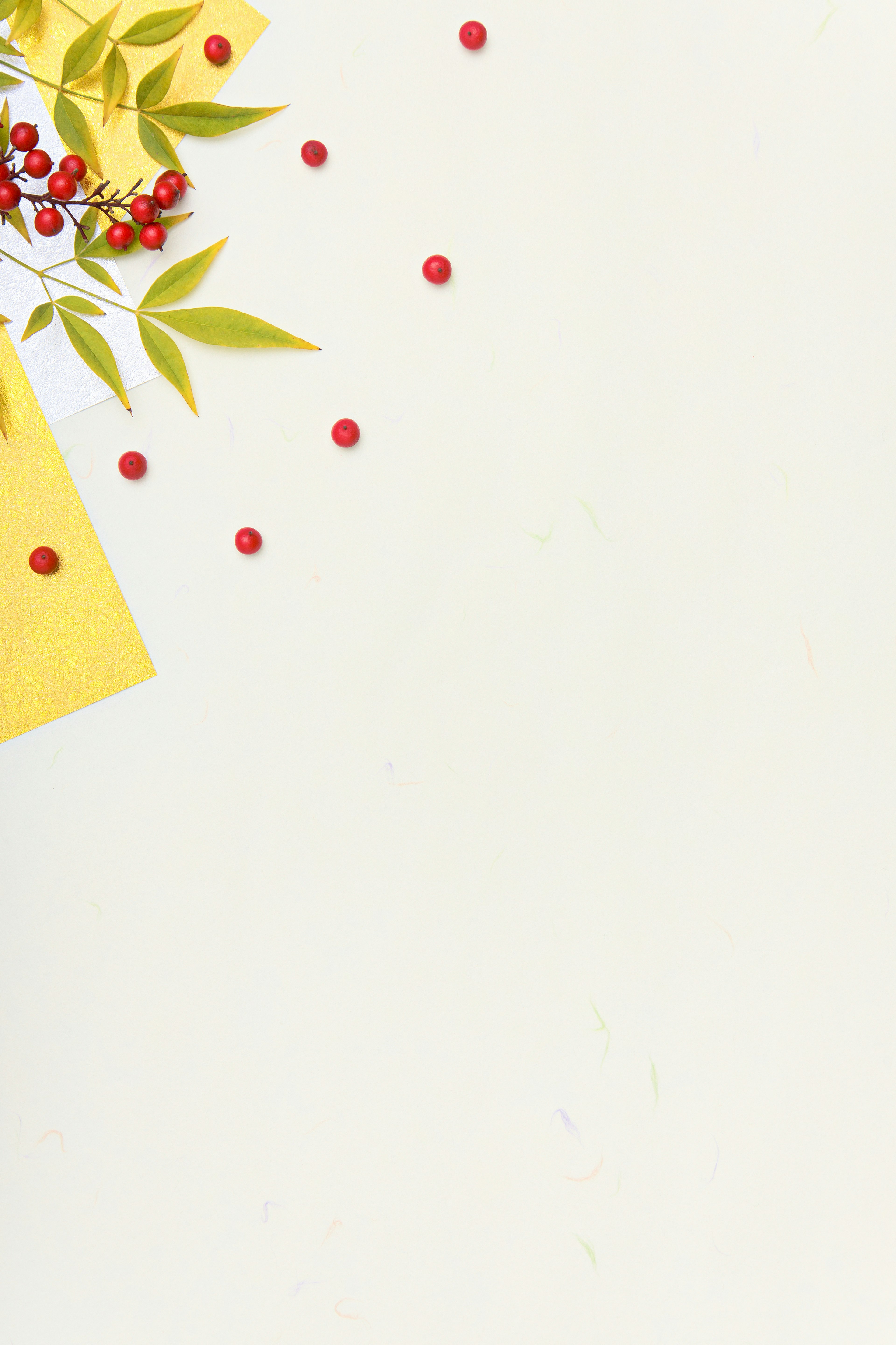 Yellow notepad with red berries and green leaves scattered on a light background