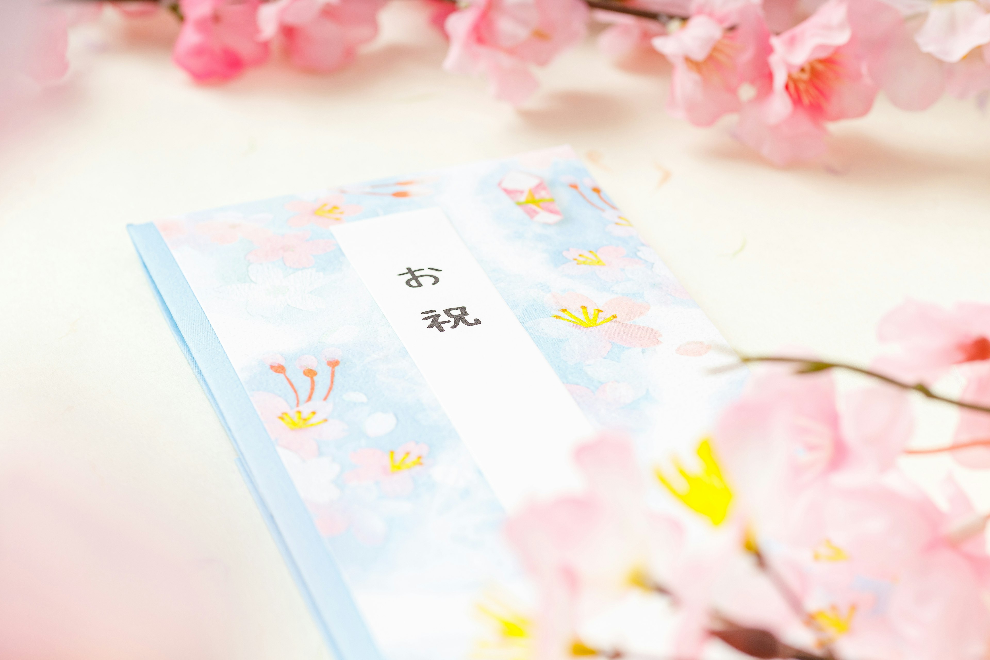 A blue covered book with celebratory text surrounded by cherry blossoms