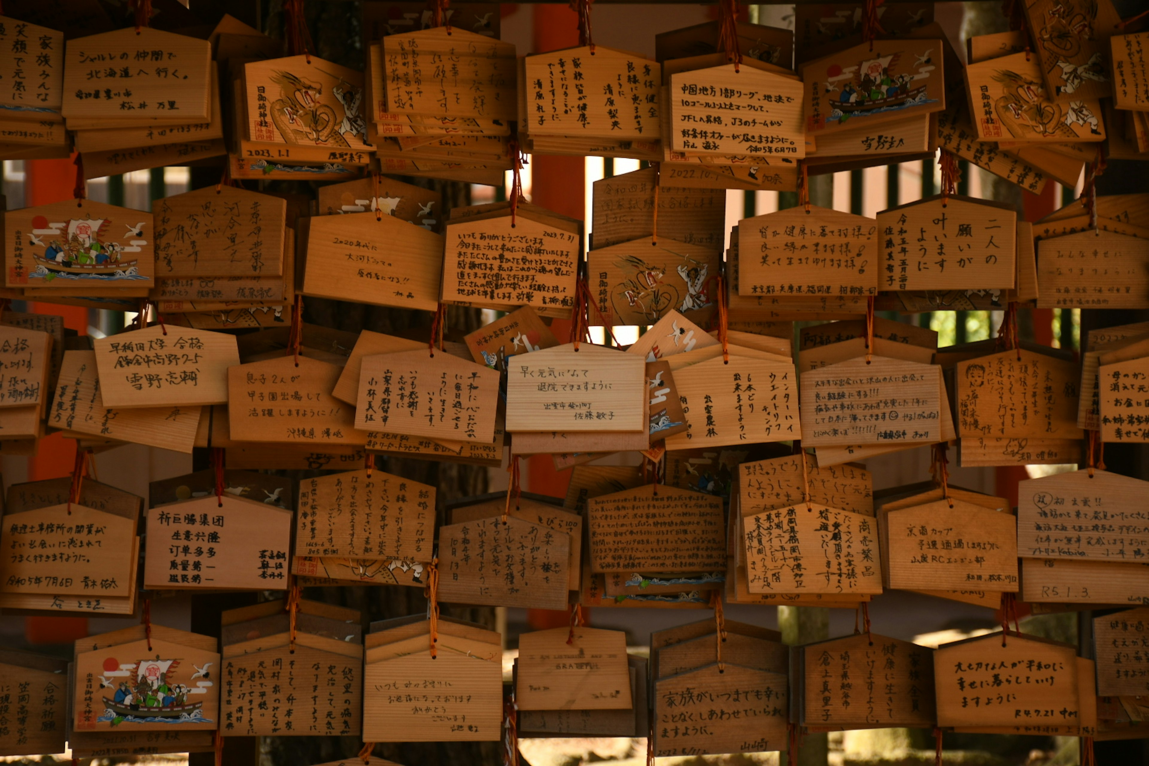 A collection of wooden ema plaques hanging in a shrine