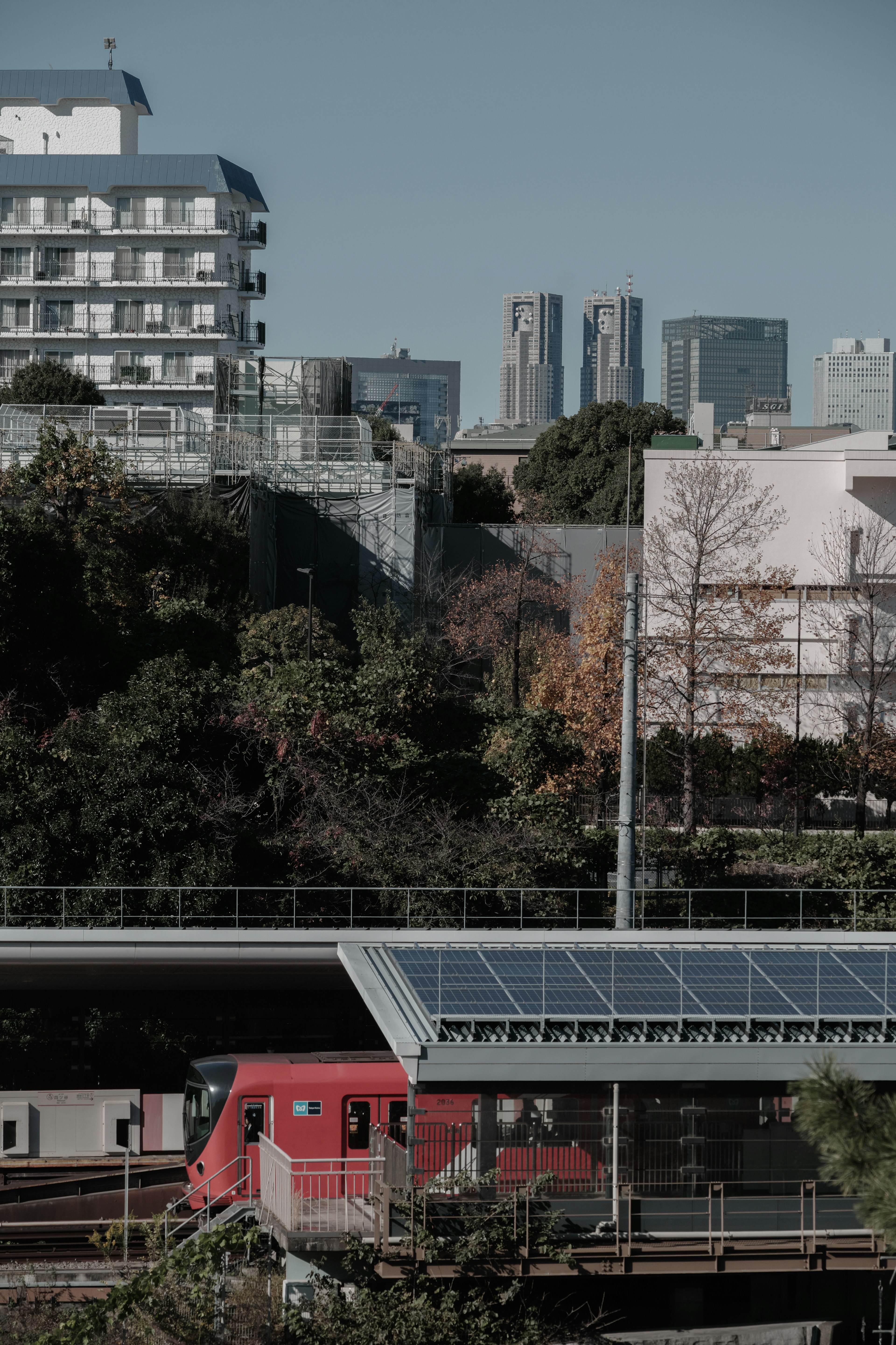 Paesaggio urbano con un treno rosso edifici e vegetazione