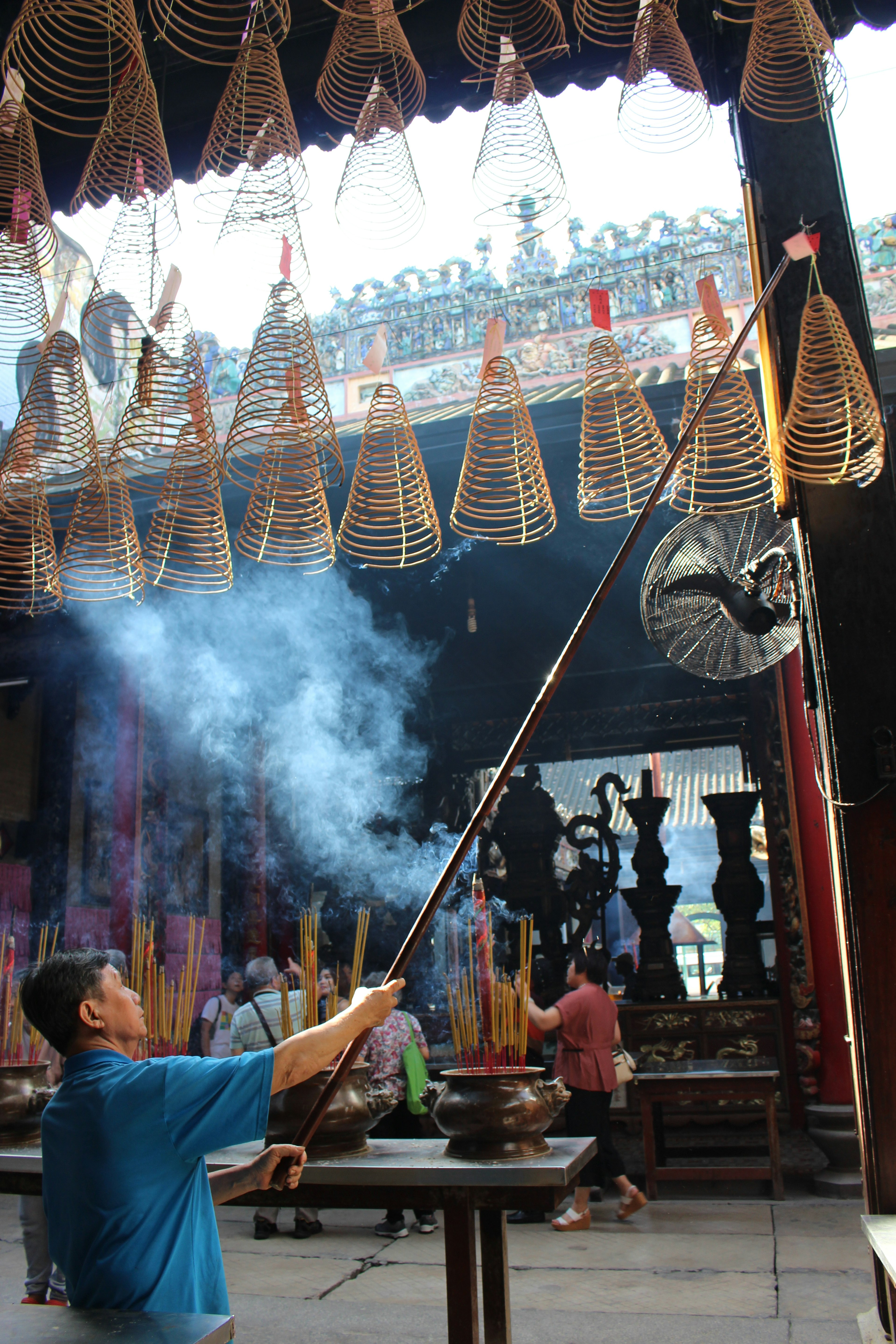 A person lighting incense in a temple with smoke rising