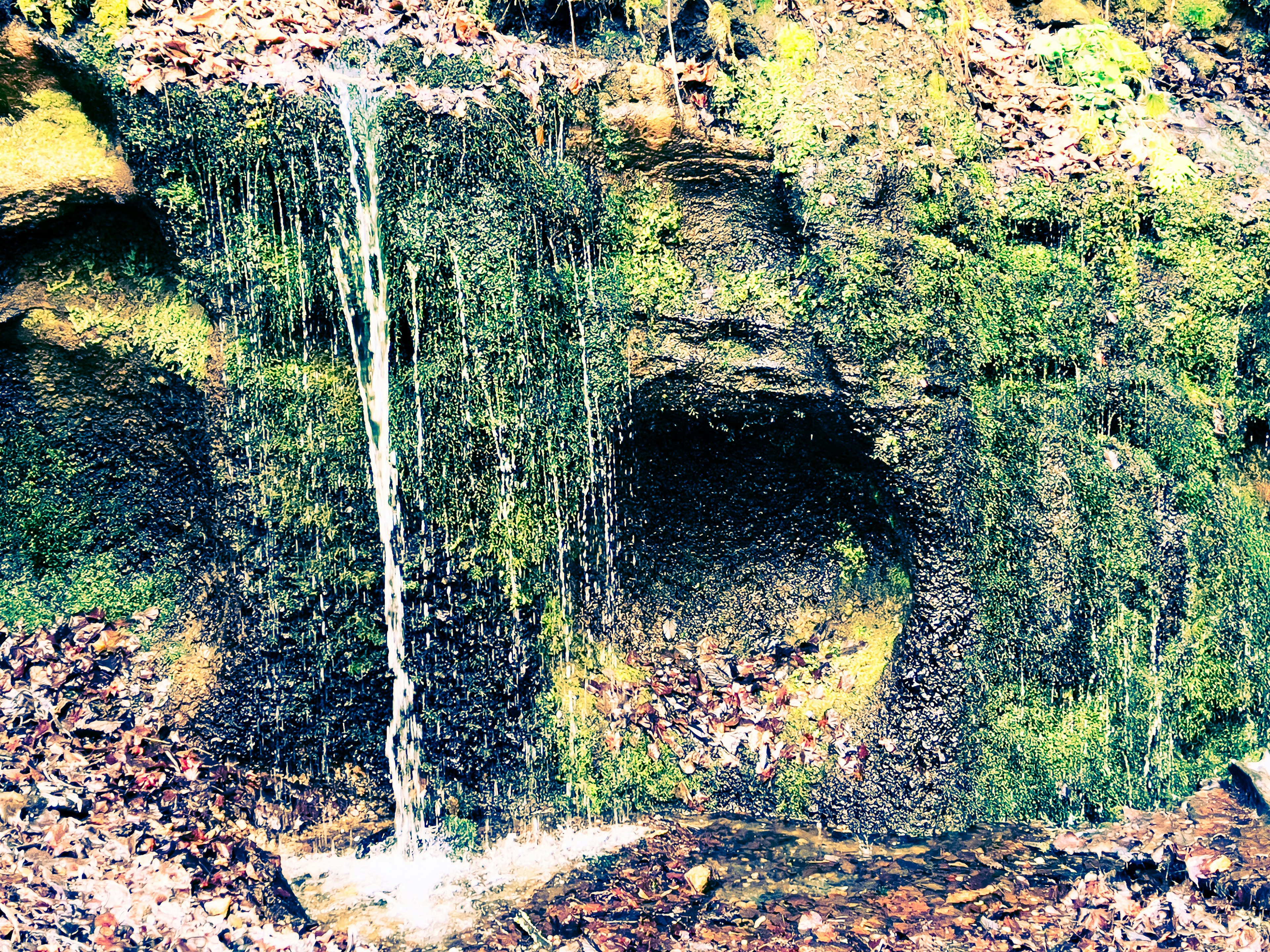 Bild eines kleinen Wasserfalls, der von einem moosbedeckten Felsen fließt