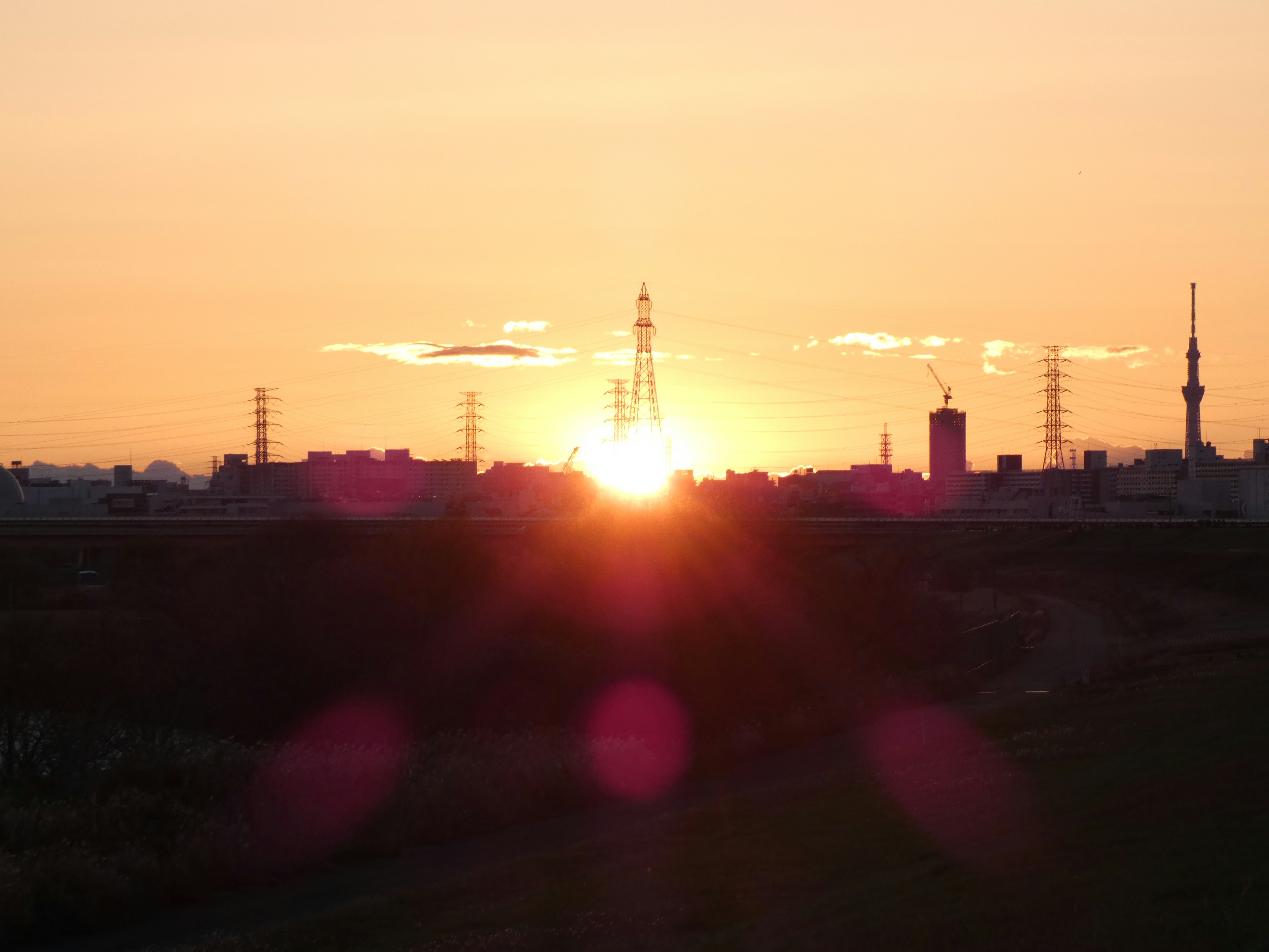 Sunset over city skyline with silhouettes of buildings and towers