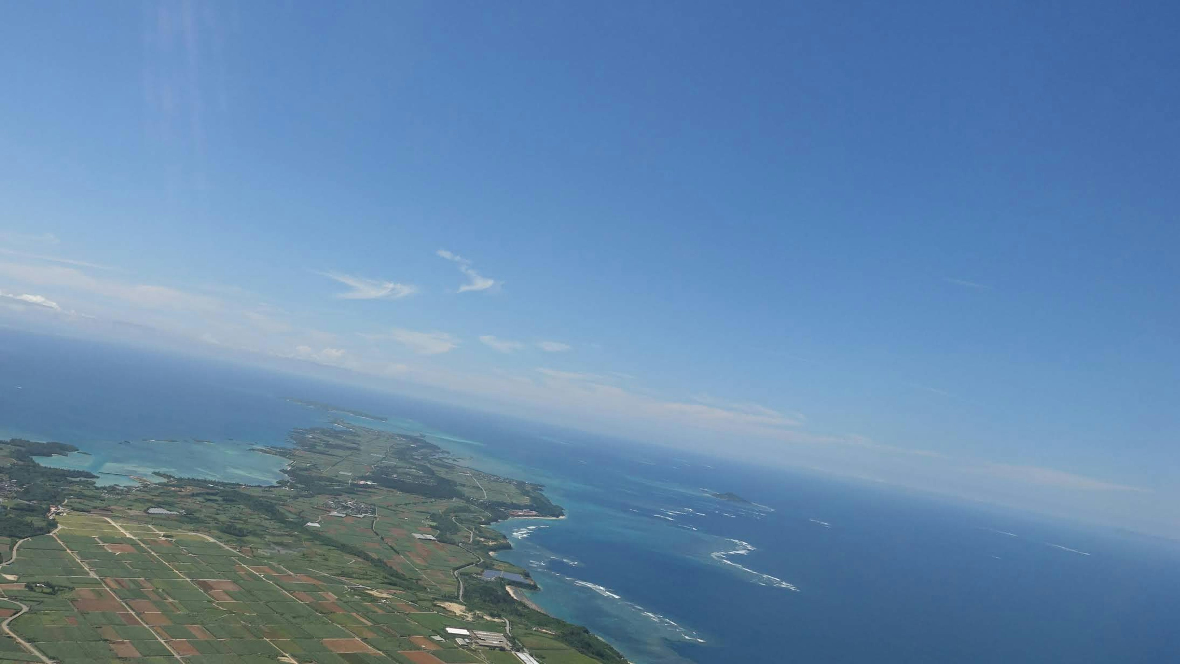 Aerial view of blue sky and ocean with green land