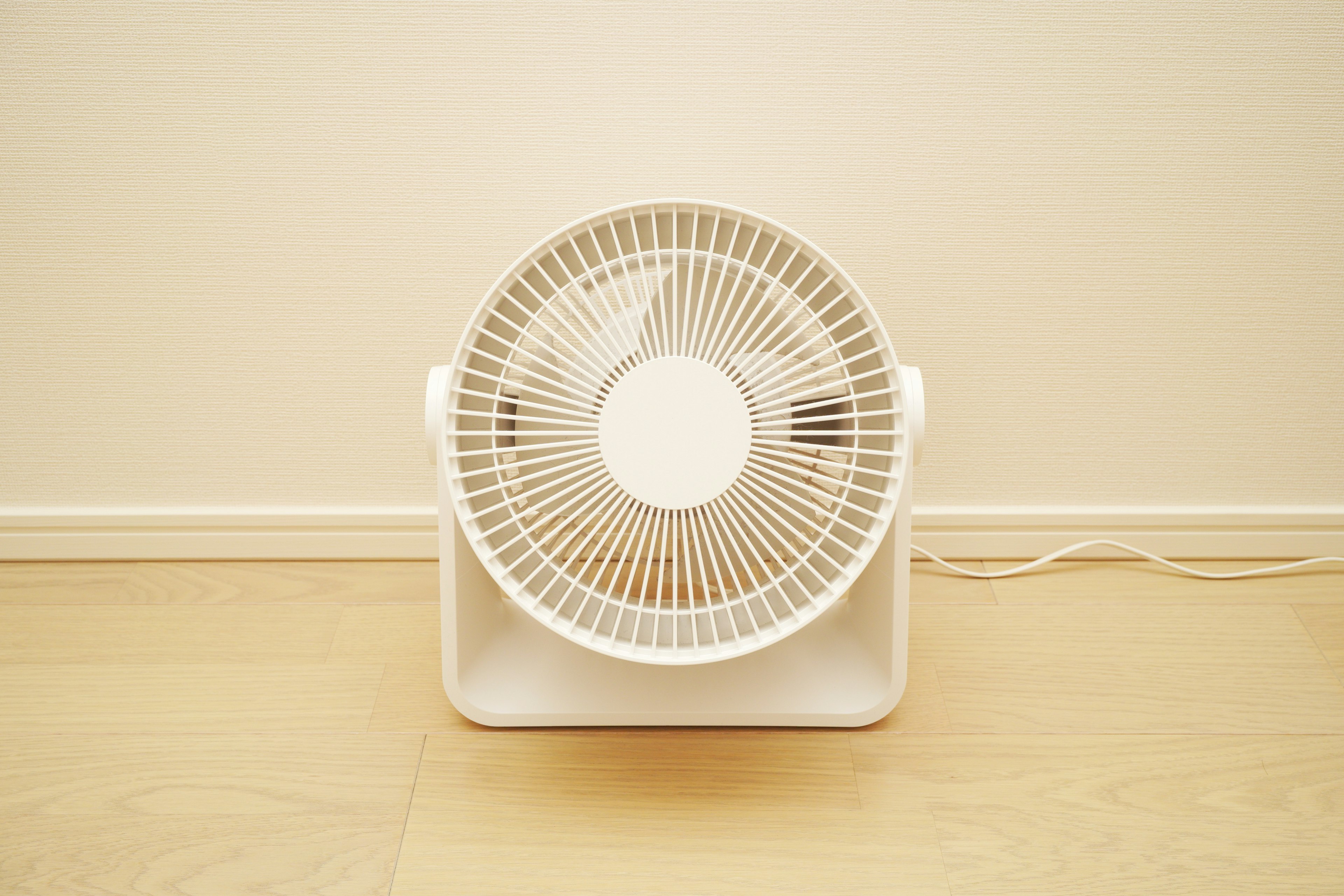 Un ventilateur blanc posé au sol dans un intérieur minimaliste