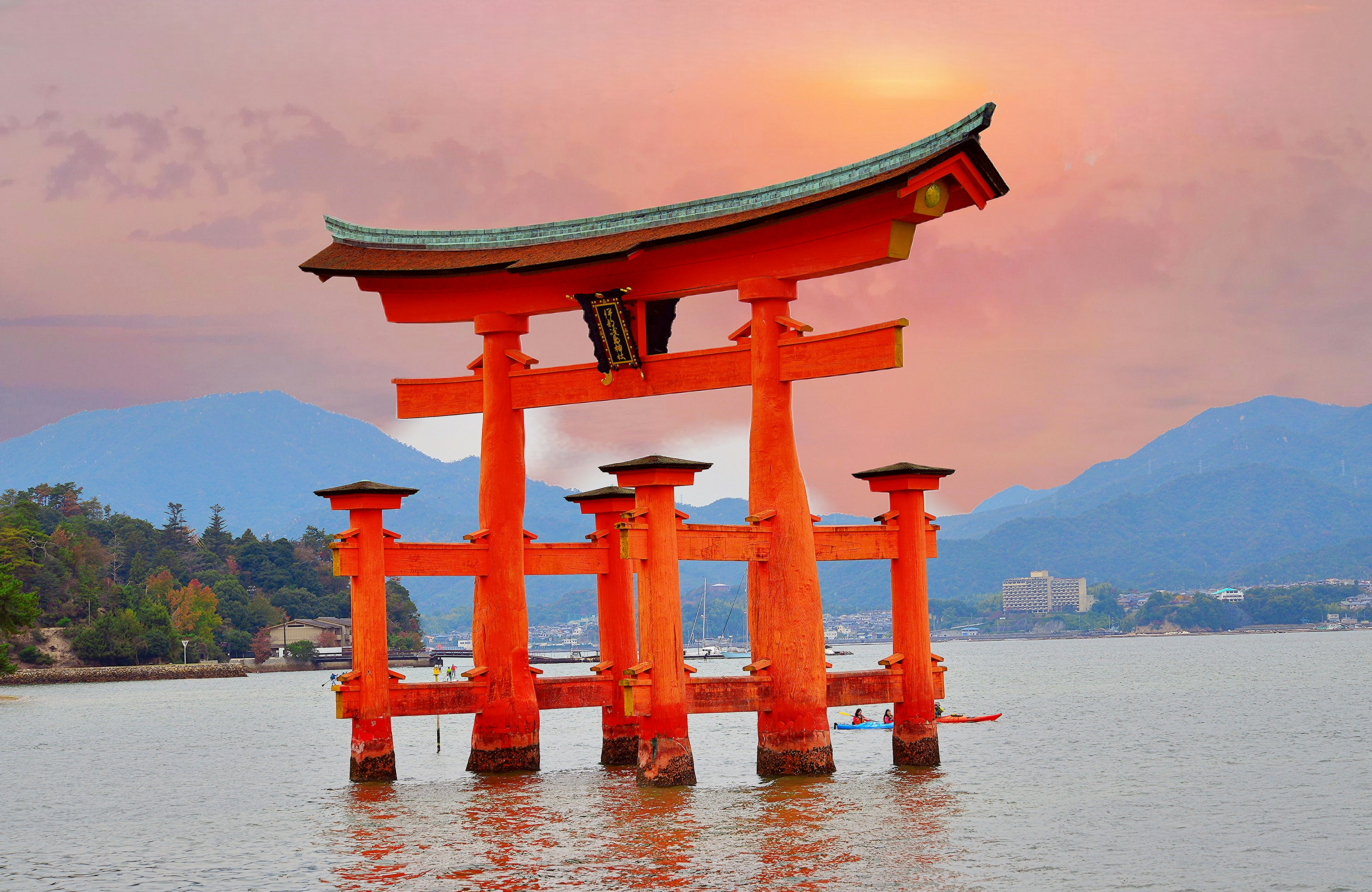 Cổng torii của đền Itsukushima đứng trong nước vào lúc hoàng hôn