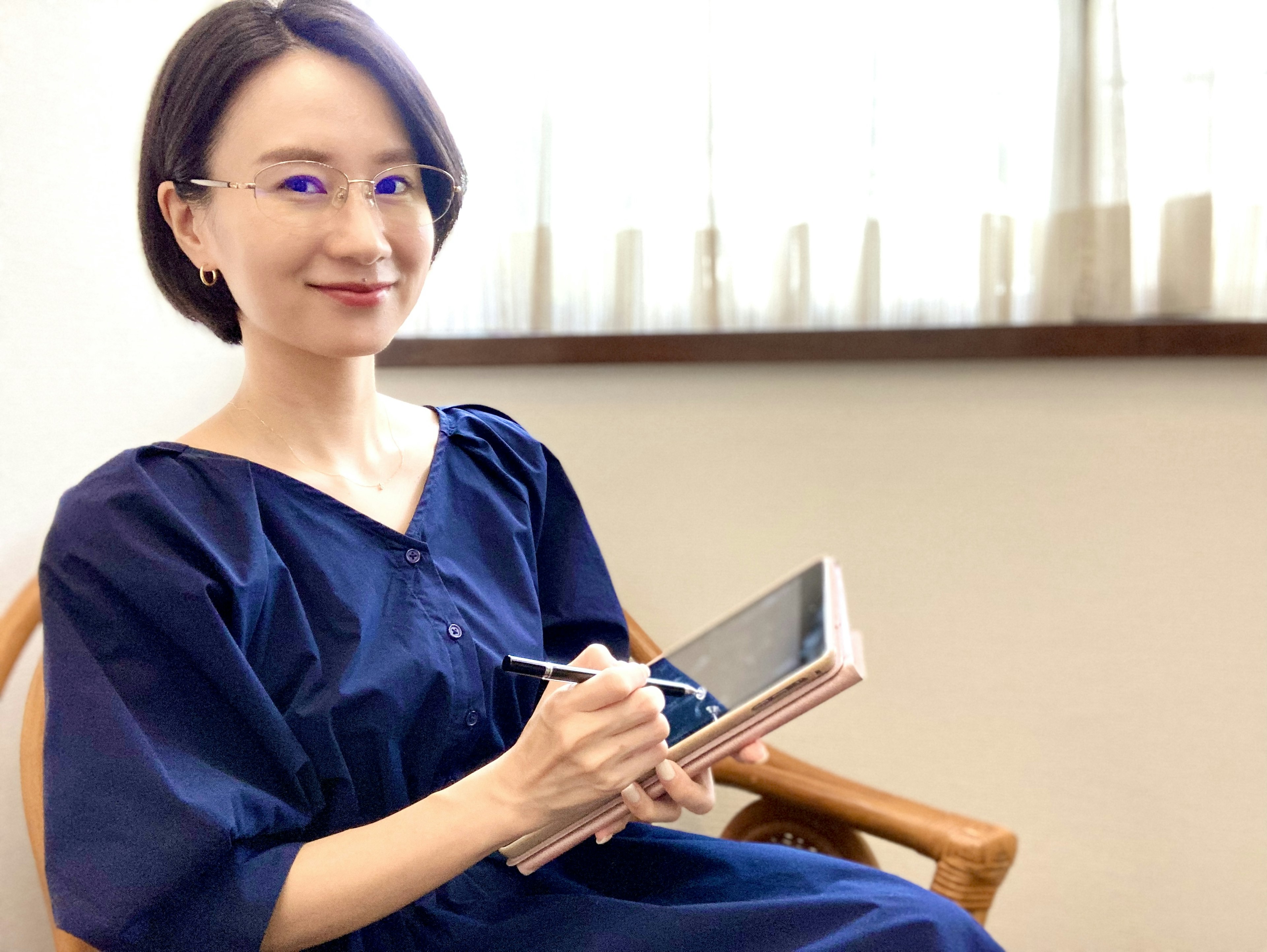 Une femme portant une robe bleue tenant une tablette souriante dans un cadre intérieur