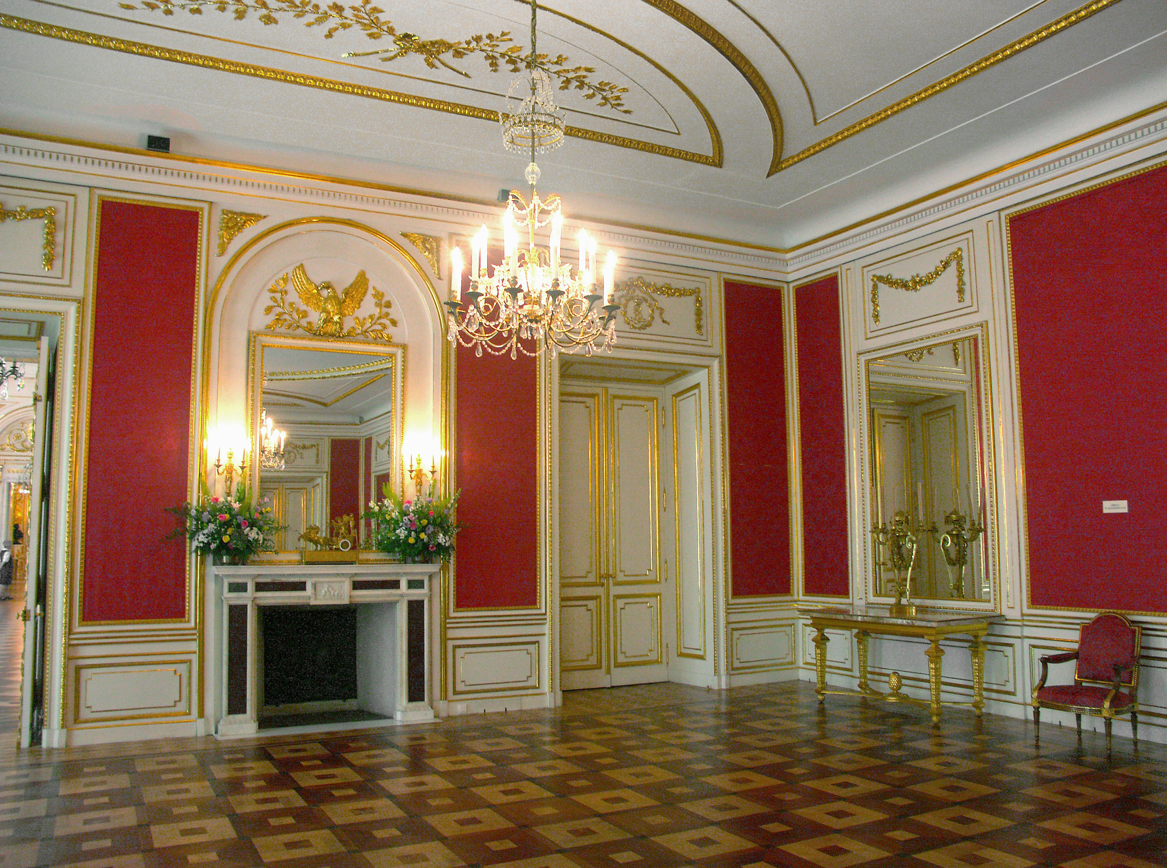 Salle élégante avec un décor orné comprenant un lustre des murs rouges et des accents dorés