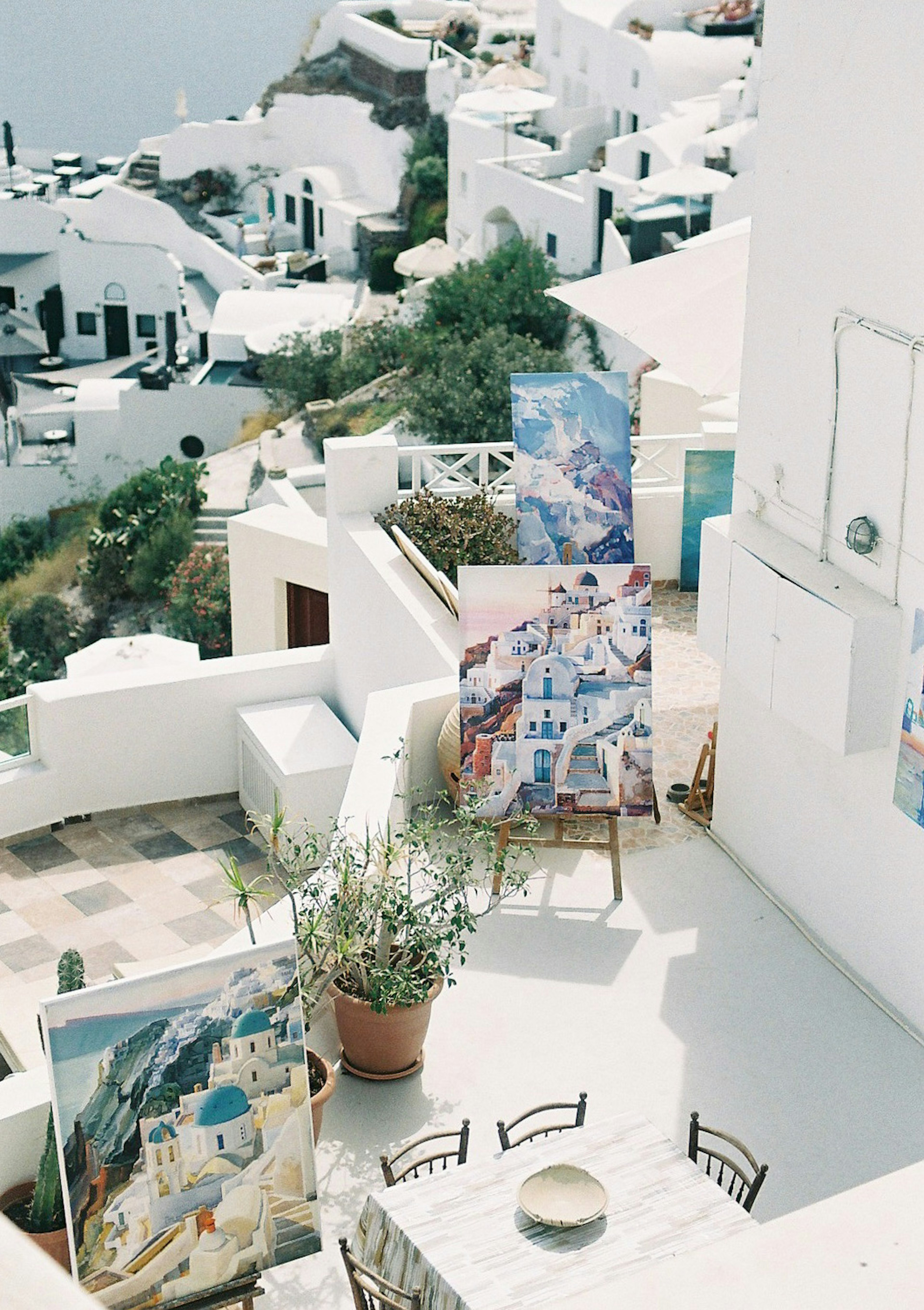 Terrace scene in Santorini featuring white buildings and displayed artwork