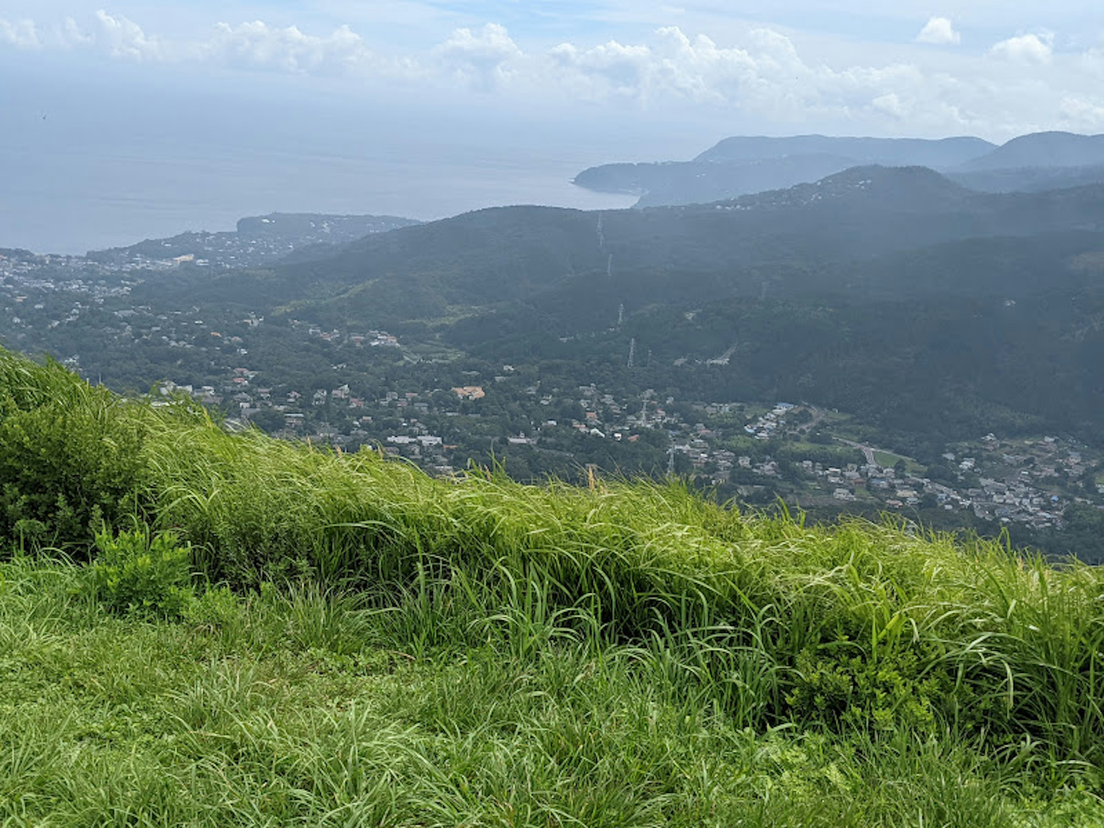 Pemandangan pegunungan dengan rumput hijau subur dan pemandangan laut