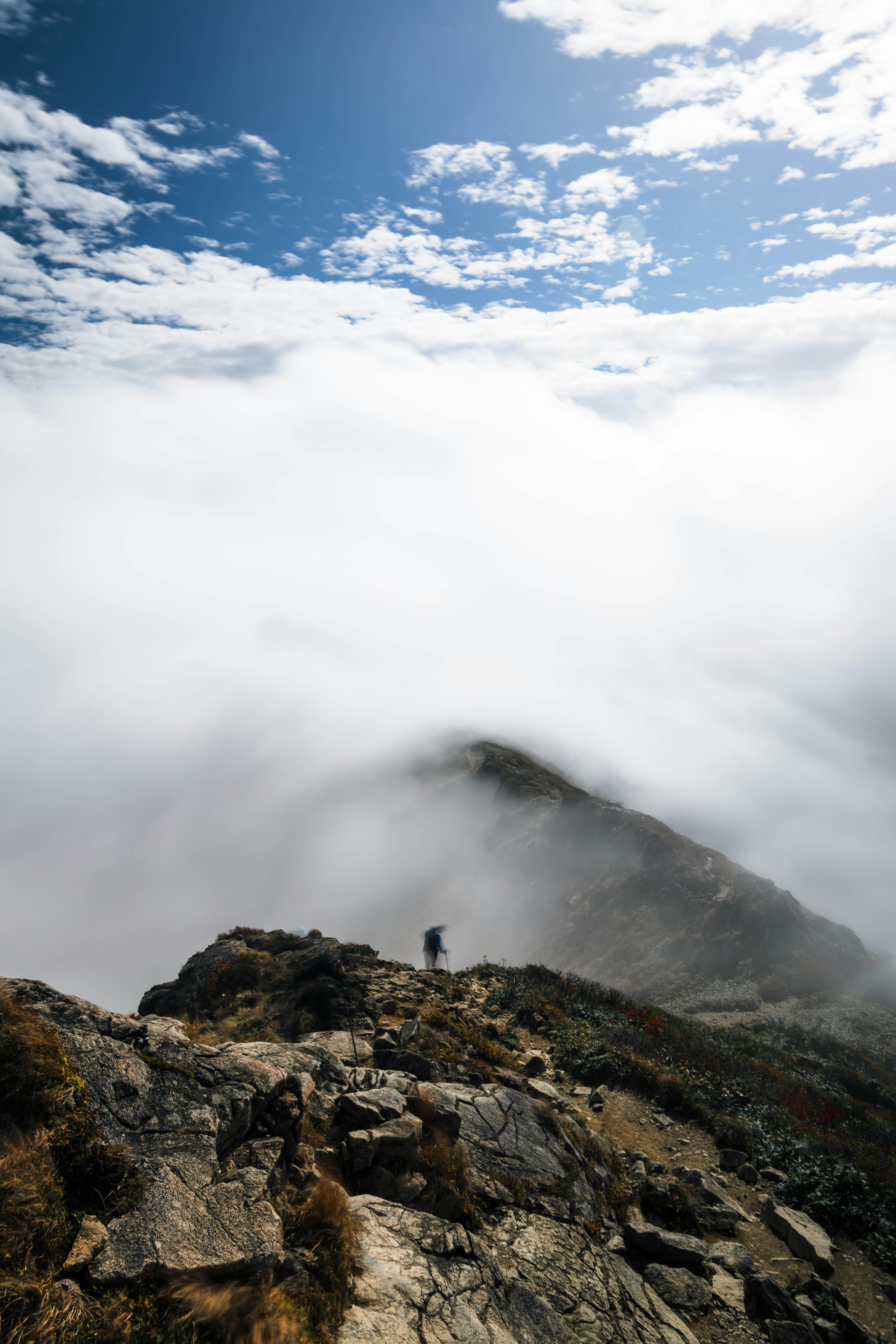 雲の中にいる登山者と青い空が広がる山の風景