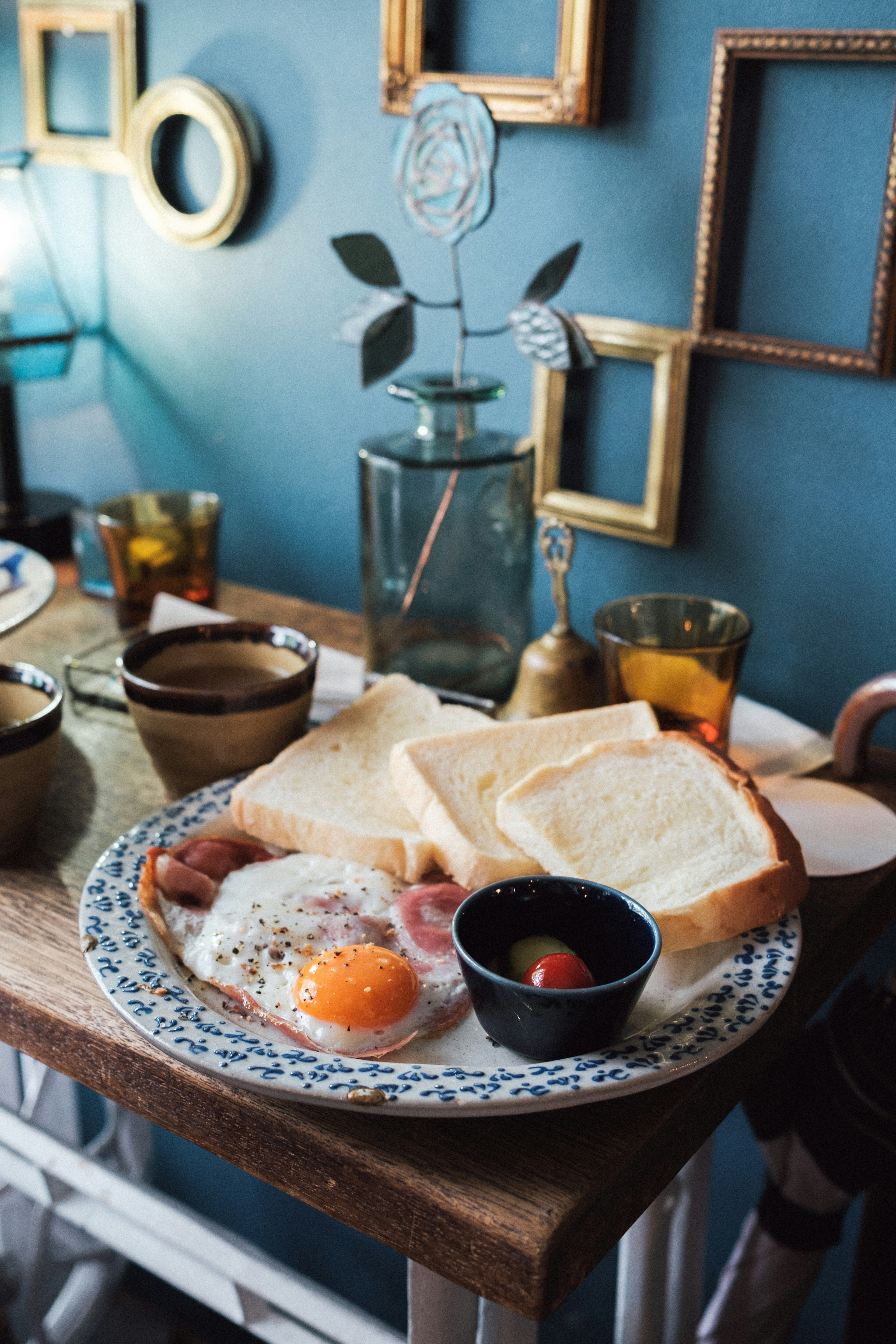 Frühstücksteller mit Toast Eiern und Kirschtomaten vor einer blauen Wand