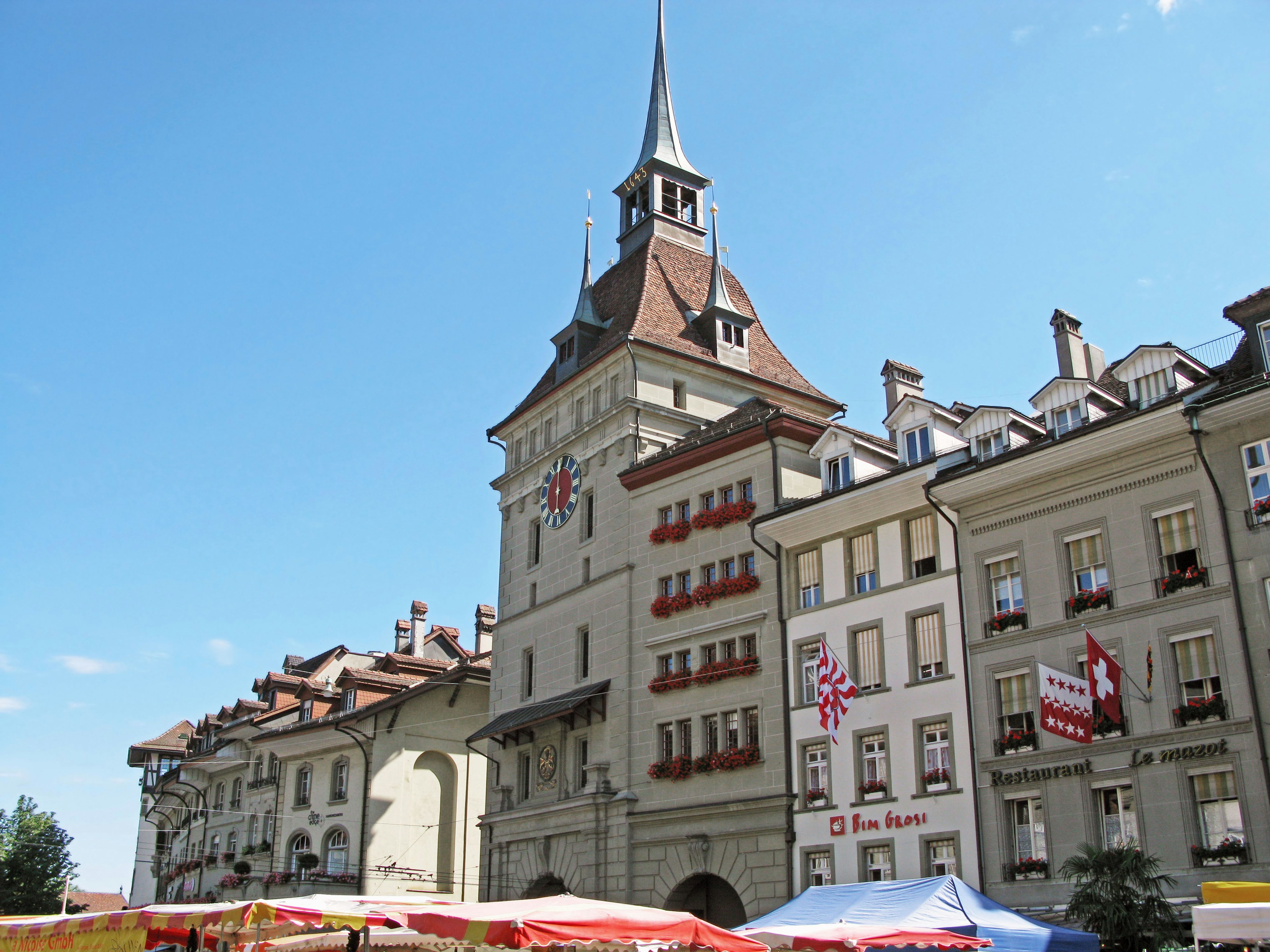 Scenic view of Swiss architecture with market stalls under a blue sky