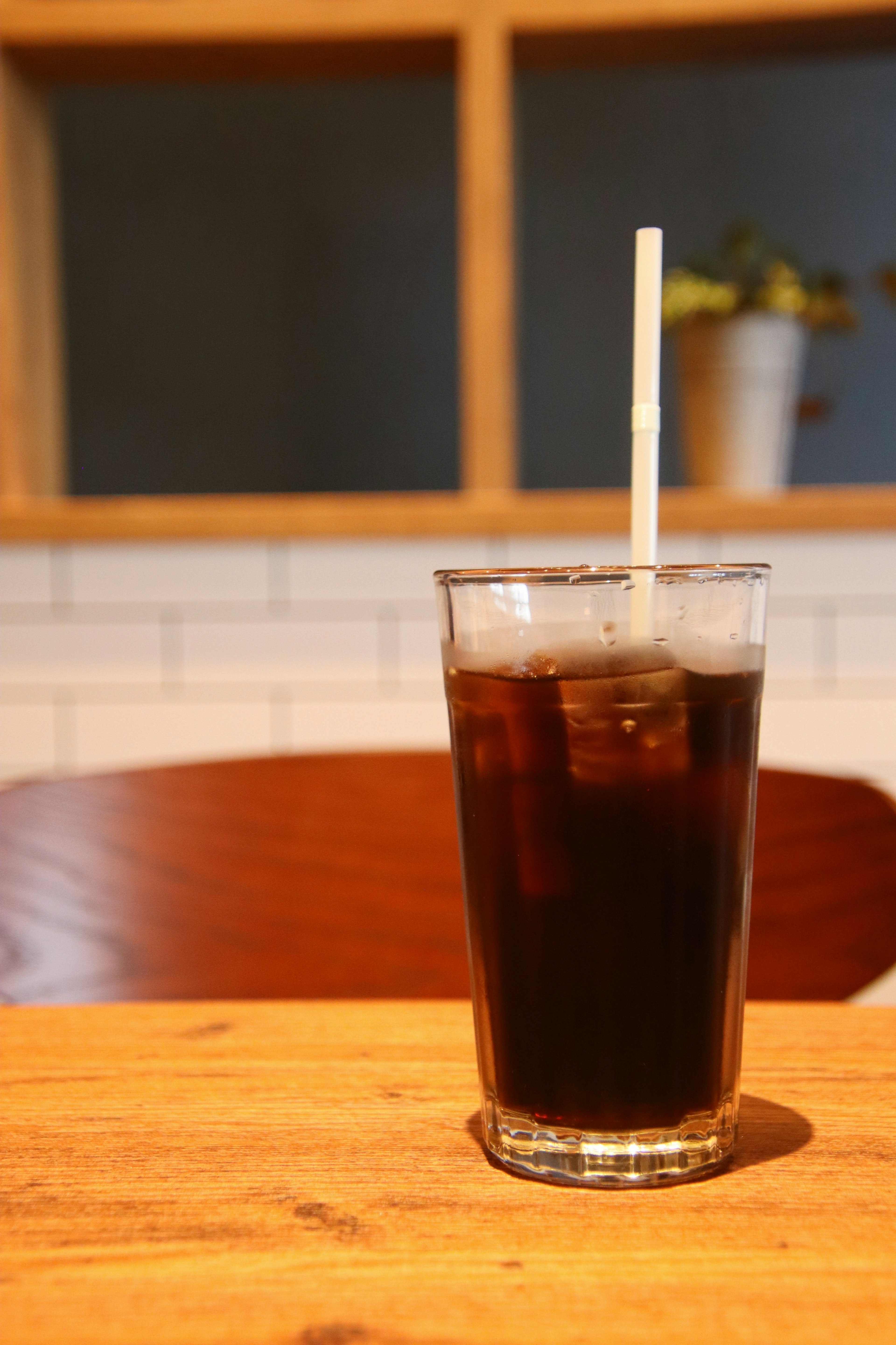 Eiskaffee in einem klaren Glas mit einem Strohhalm auf einem Holztischhintergrund