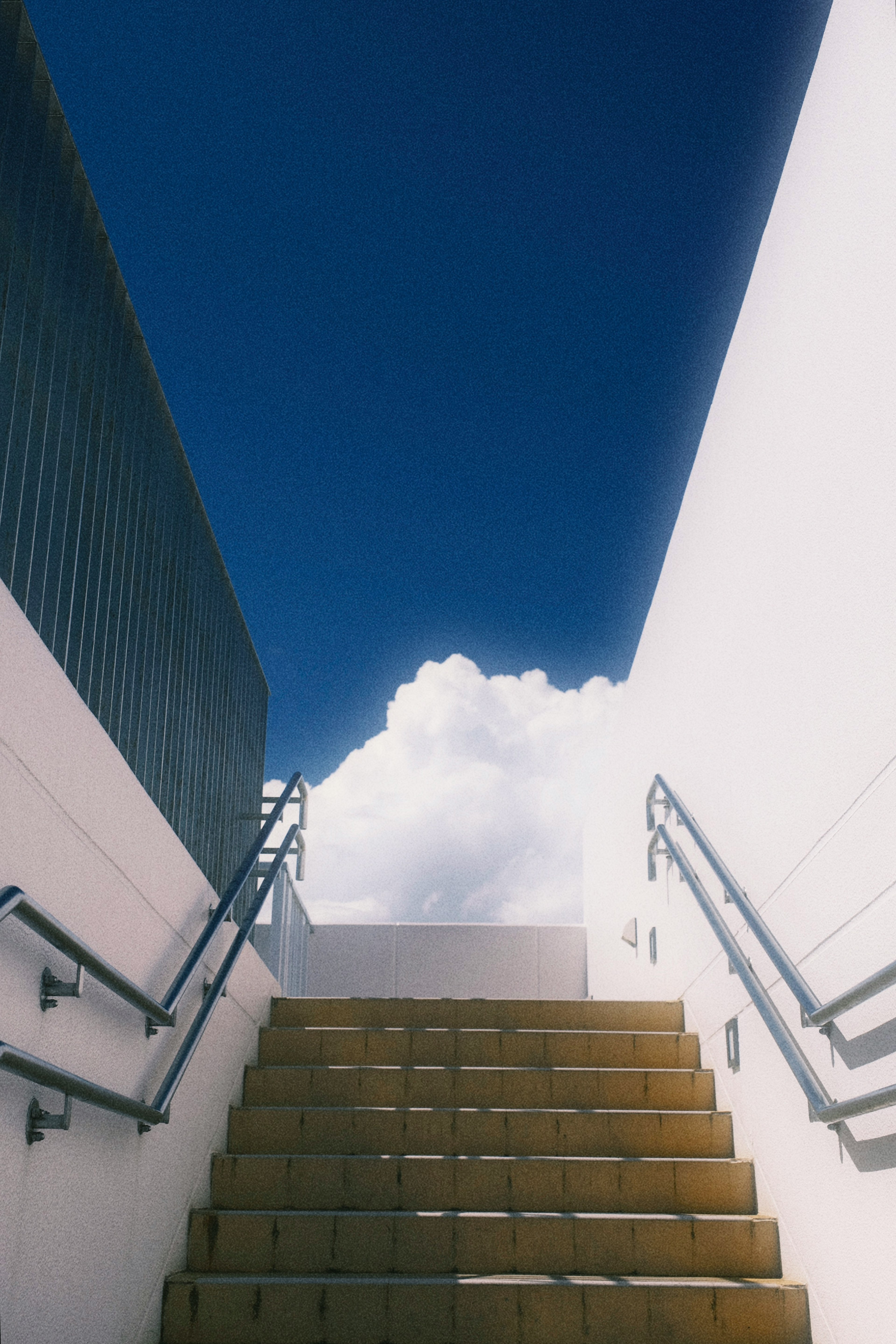 Stairs leading up towards a blue sky with white clouds