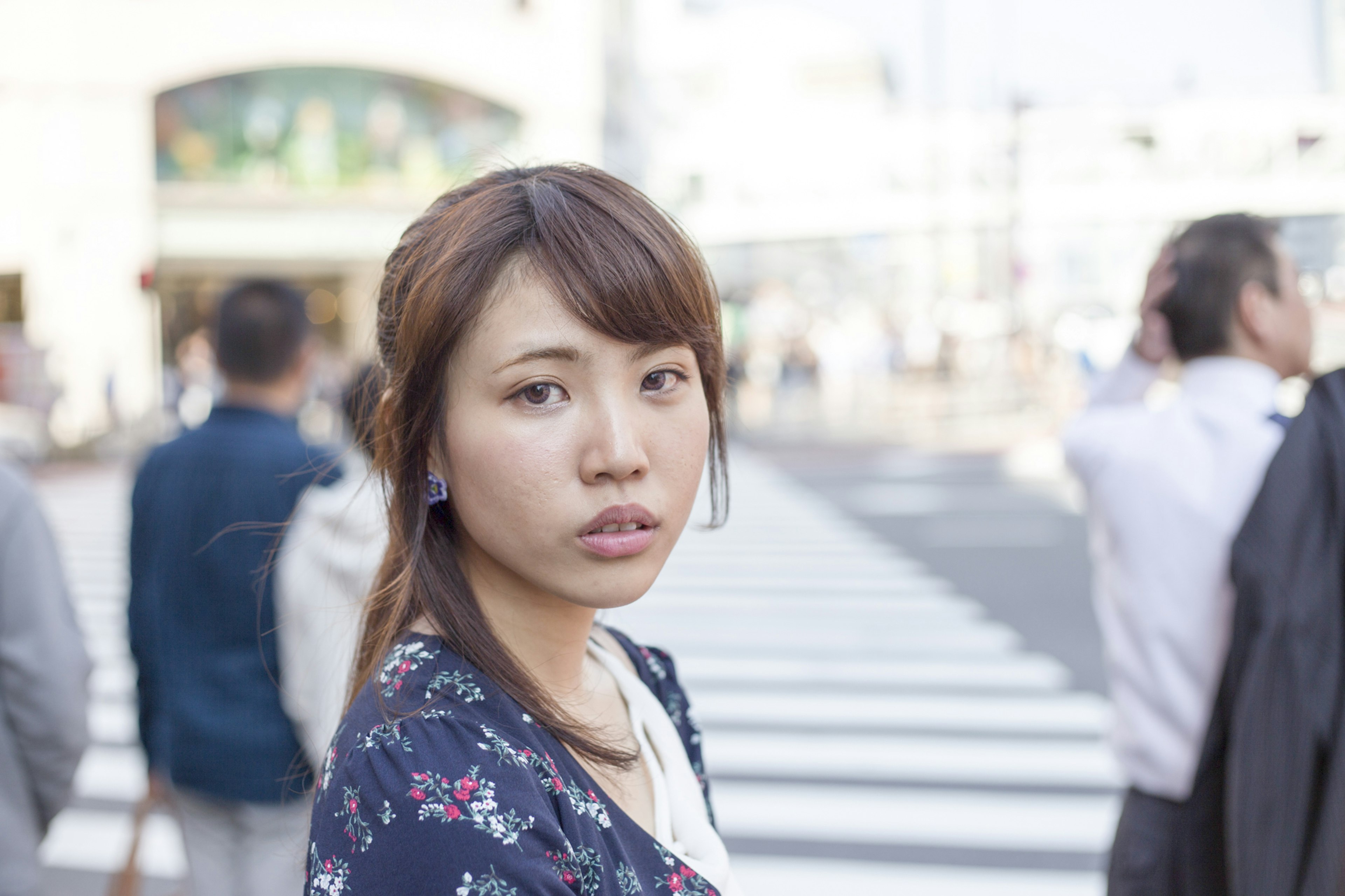 A woman looking back near a pedestrian crossing with people and a crosswalk in the background