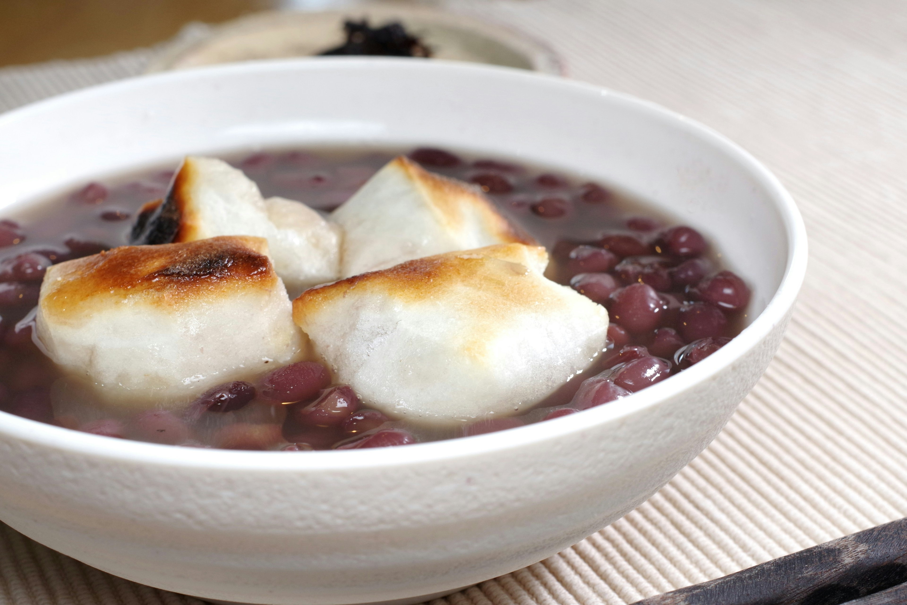 Sopa dulce de frijoles rojos con pasteles de arroz tostados en un tazón blanco