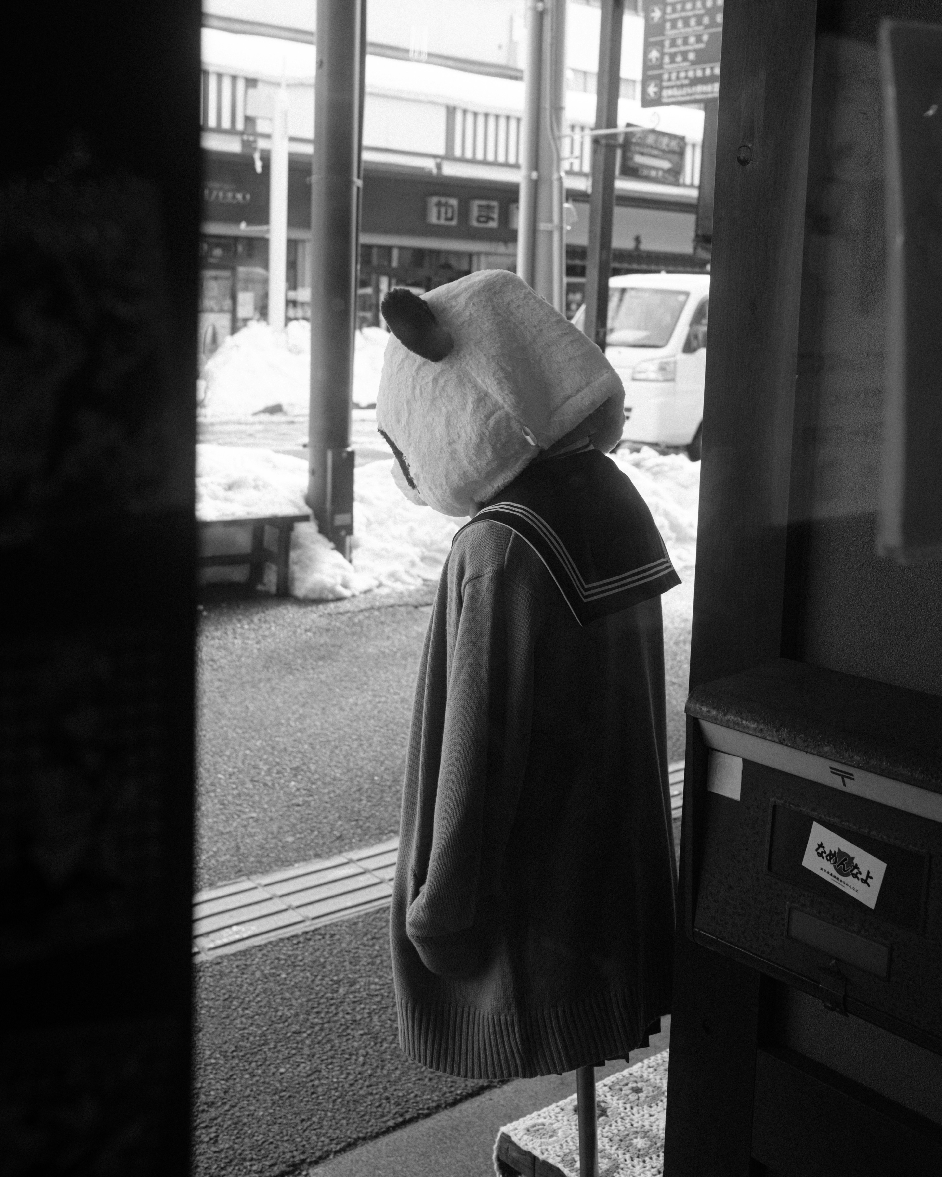 Un'immagine in bianco e nero di un personaggio in uniforme da marinaio con una maschera di animale in piedi