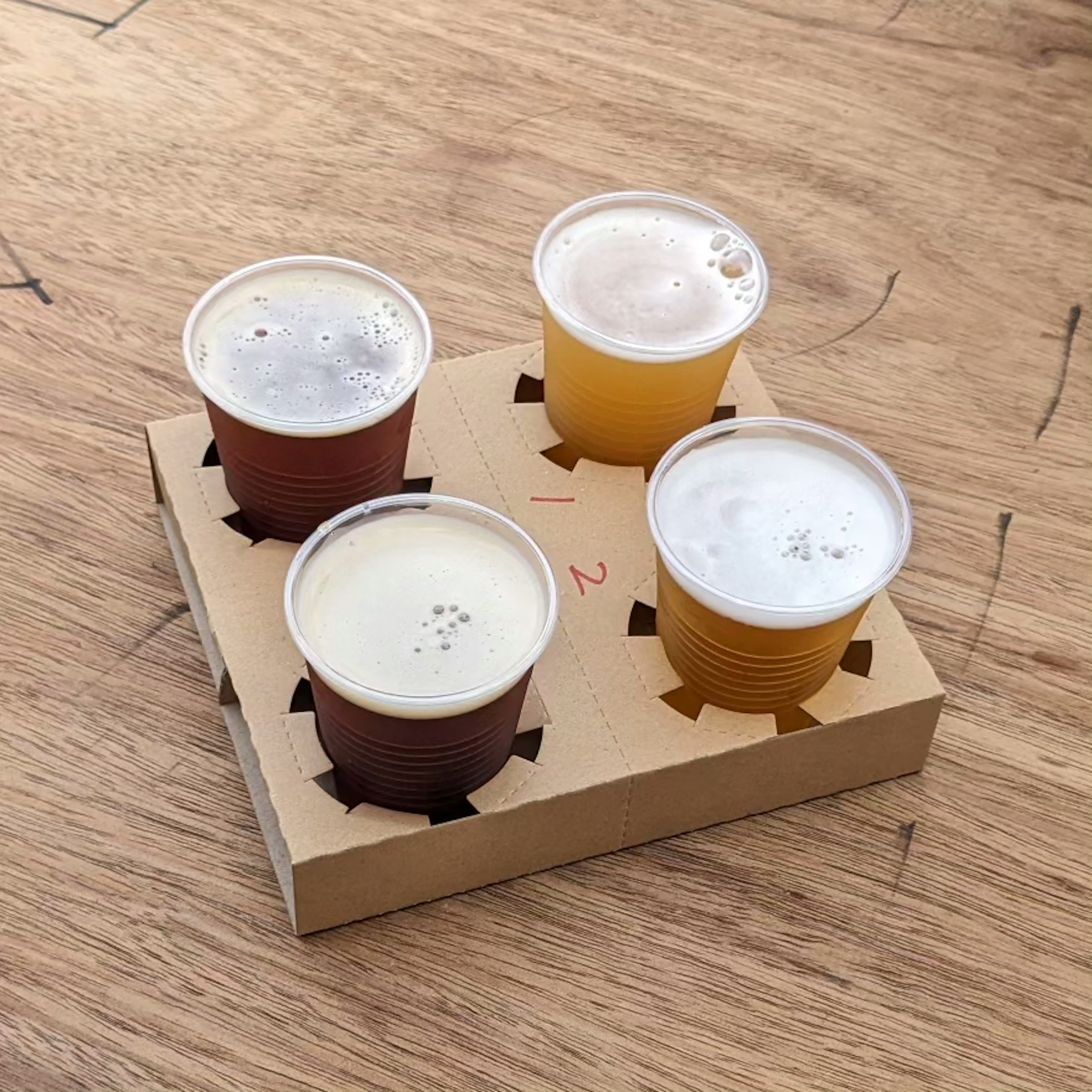 Ein Flight mit vier Bierbechern auf einem Holztisch