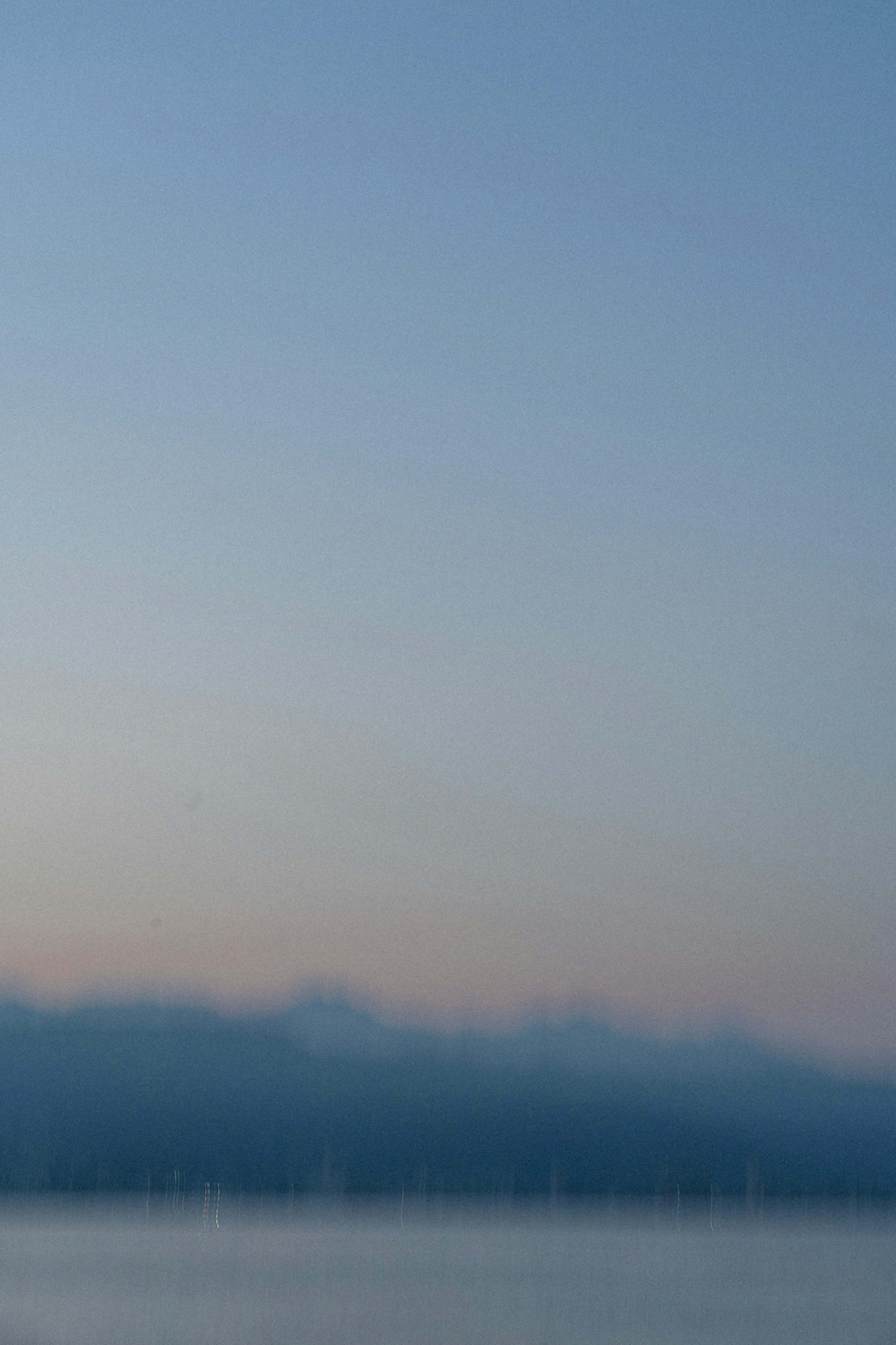 Softly lit coastline with a blue sky and distant mountains