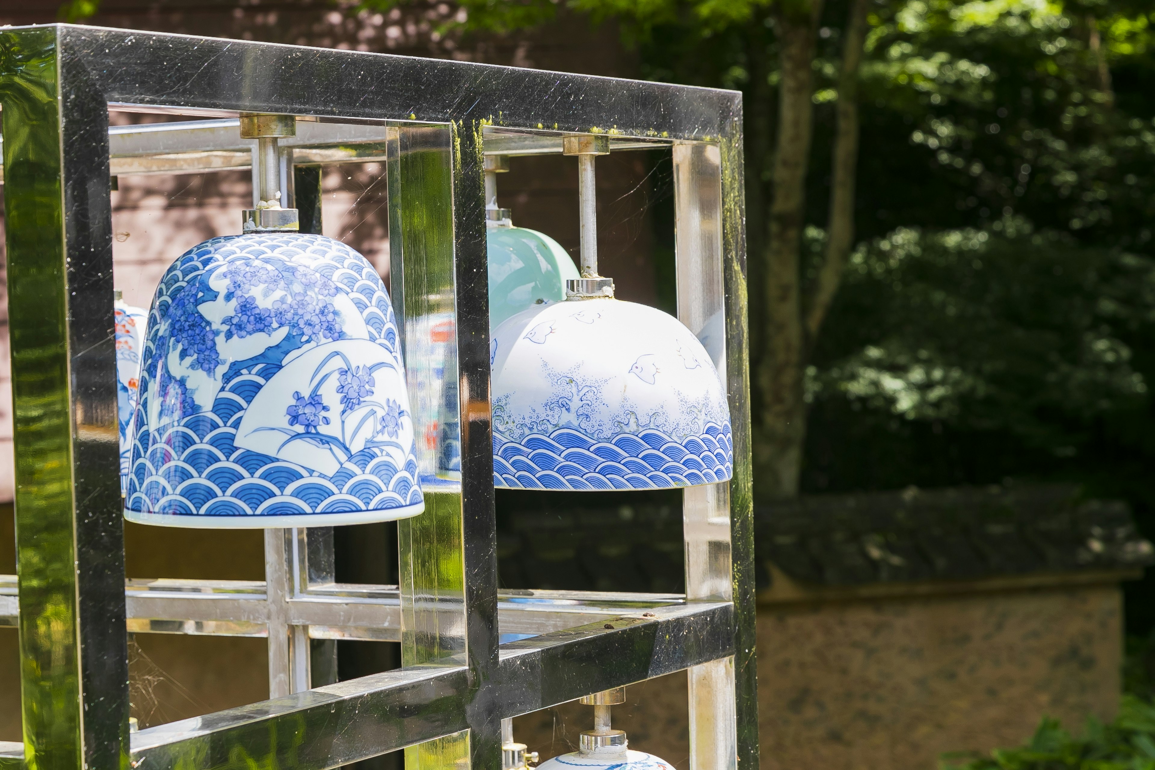 Display of decorative blue ceramic bells on a transparent stand