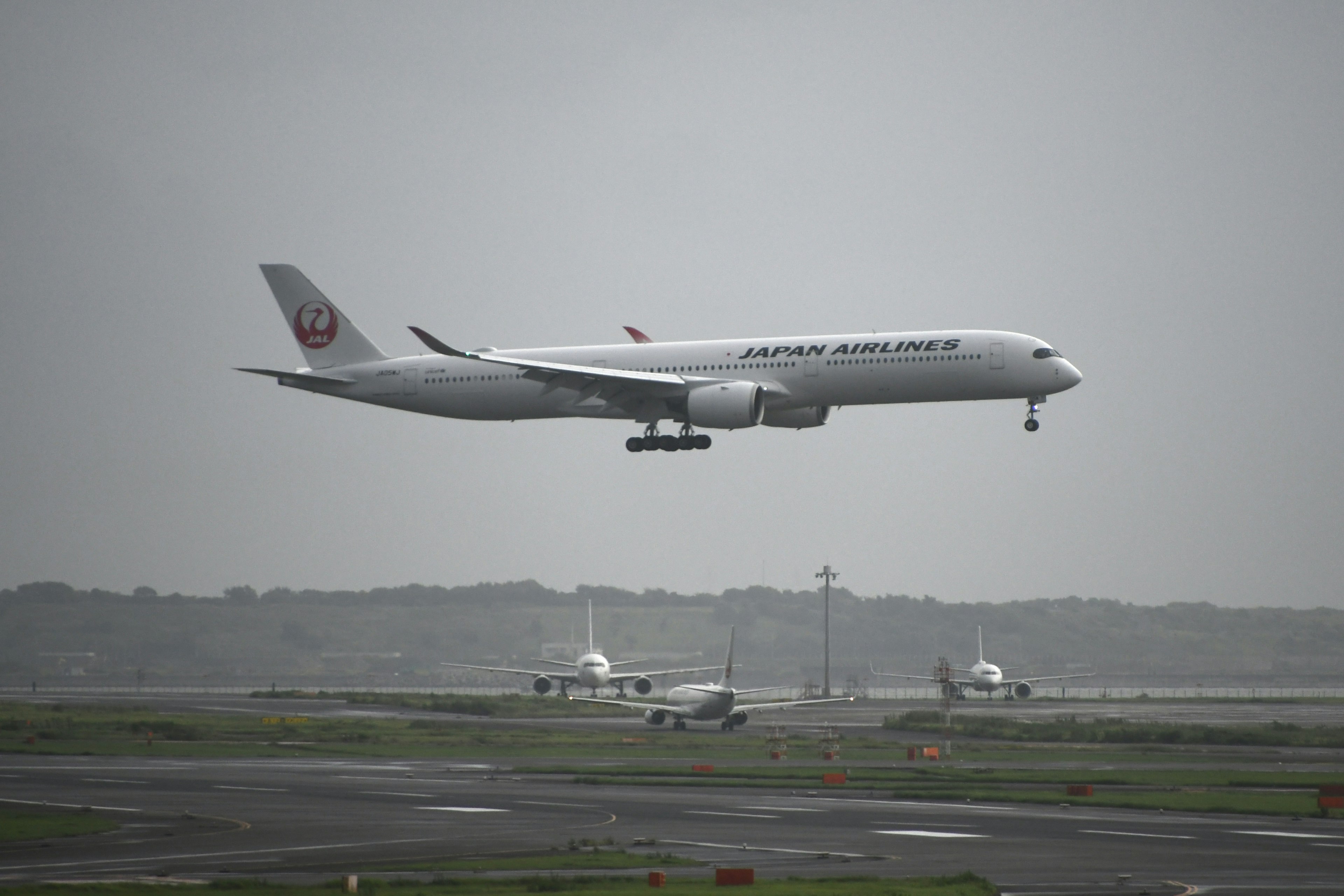 日本航空飛機在陰雲密布的天空中降落