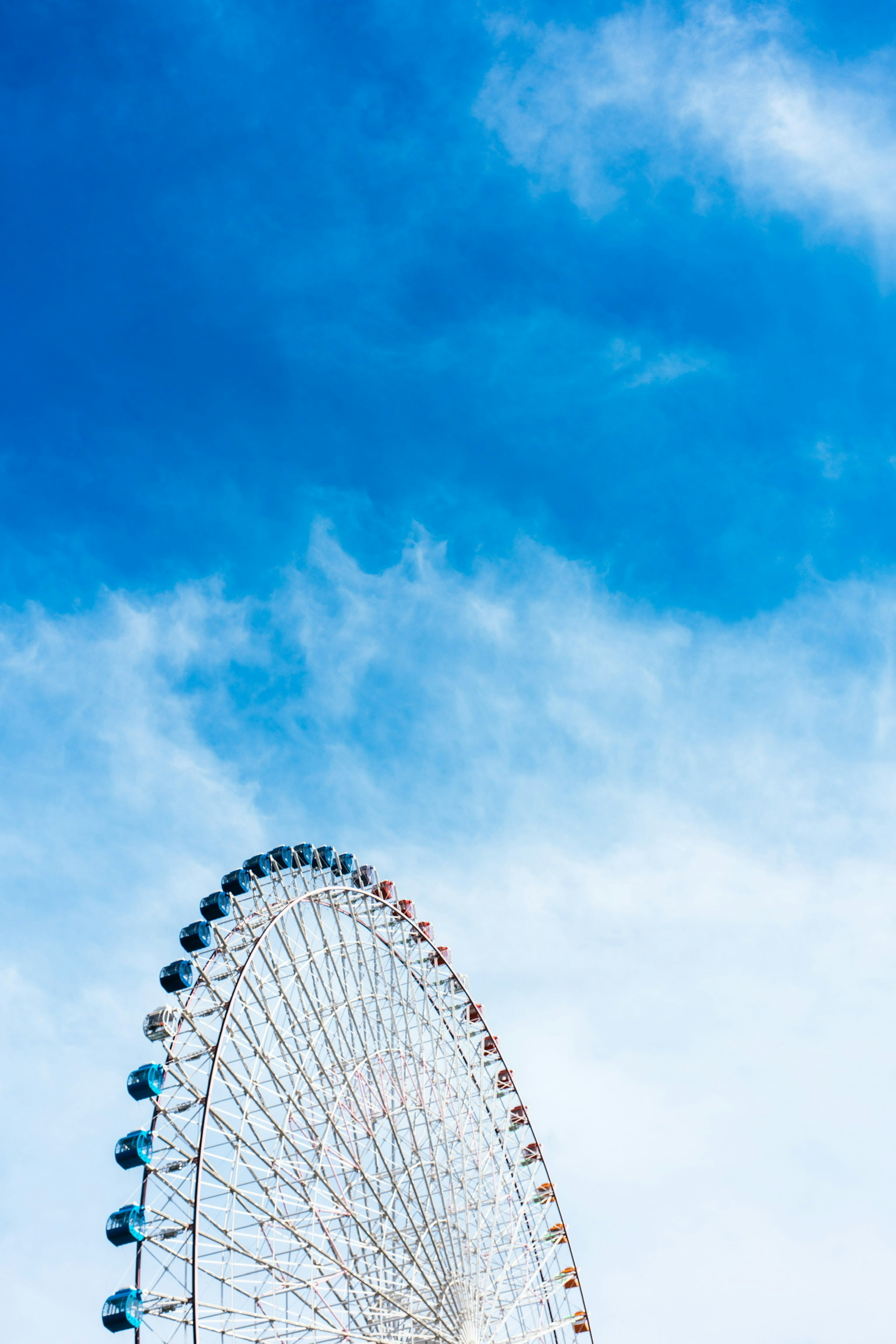 Part of a Ferris wheel under a blue sky