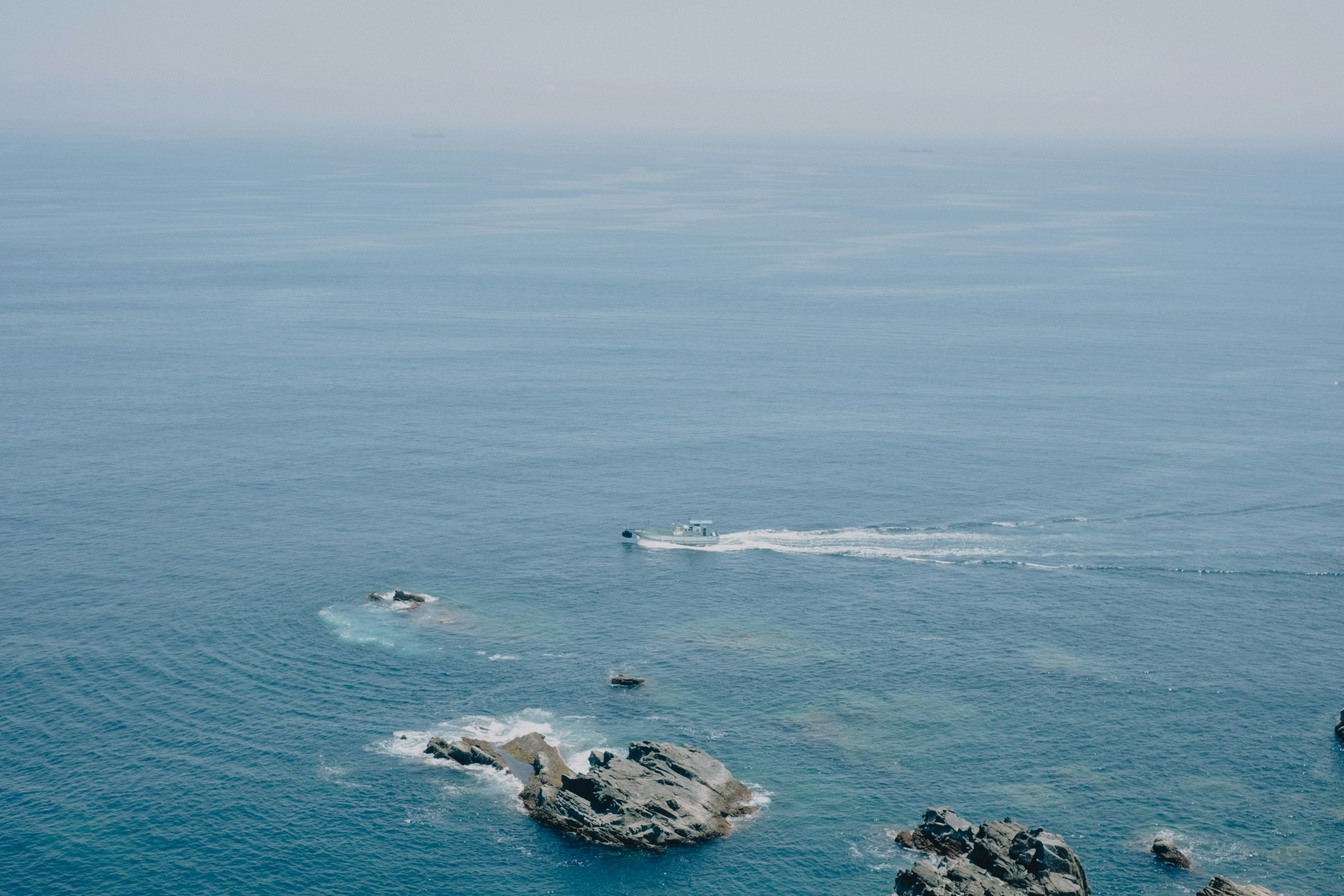 A boat navigating through blue waters near rocky islands