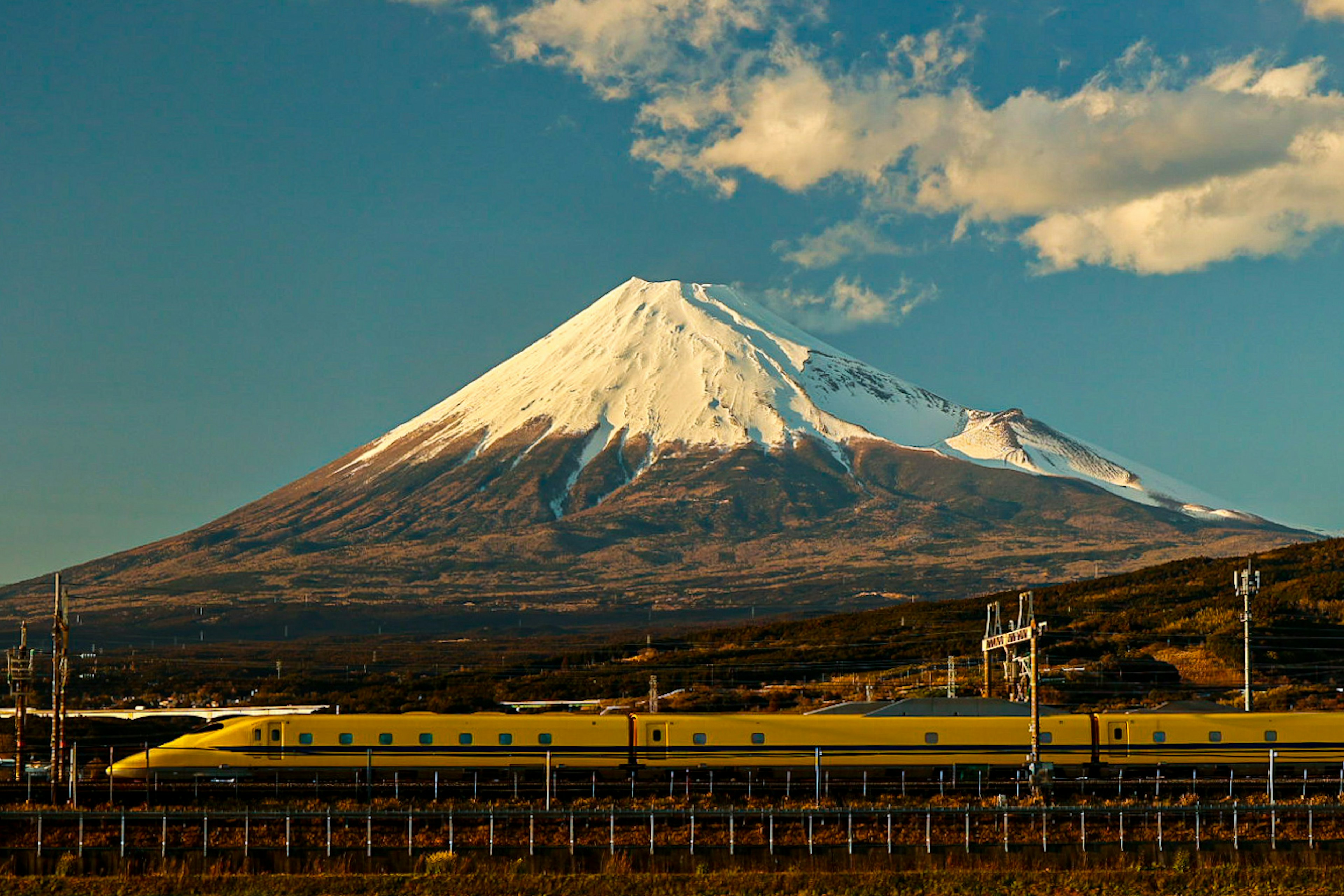 Snow-capped Mount Fuji with a yellow Shinkansen train