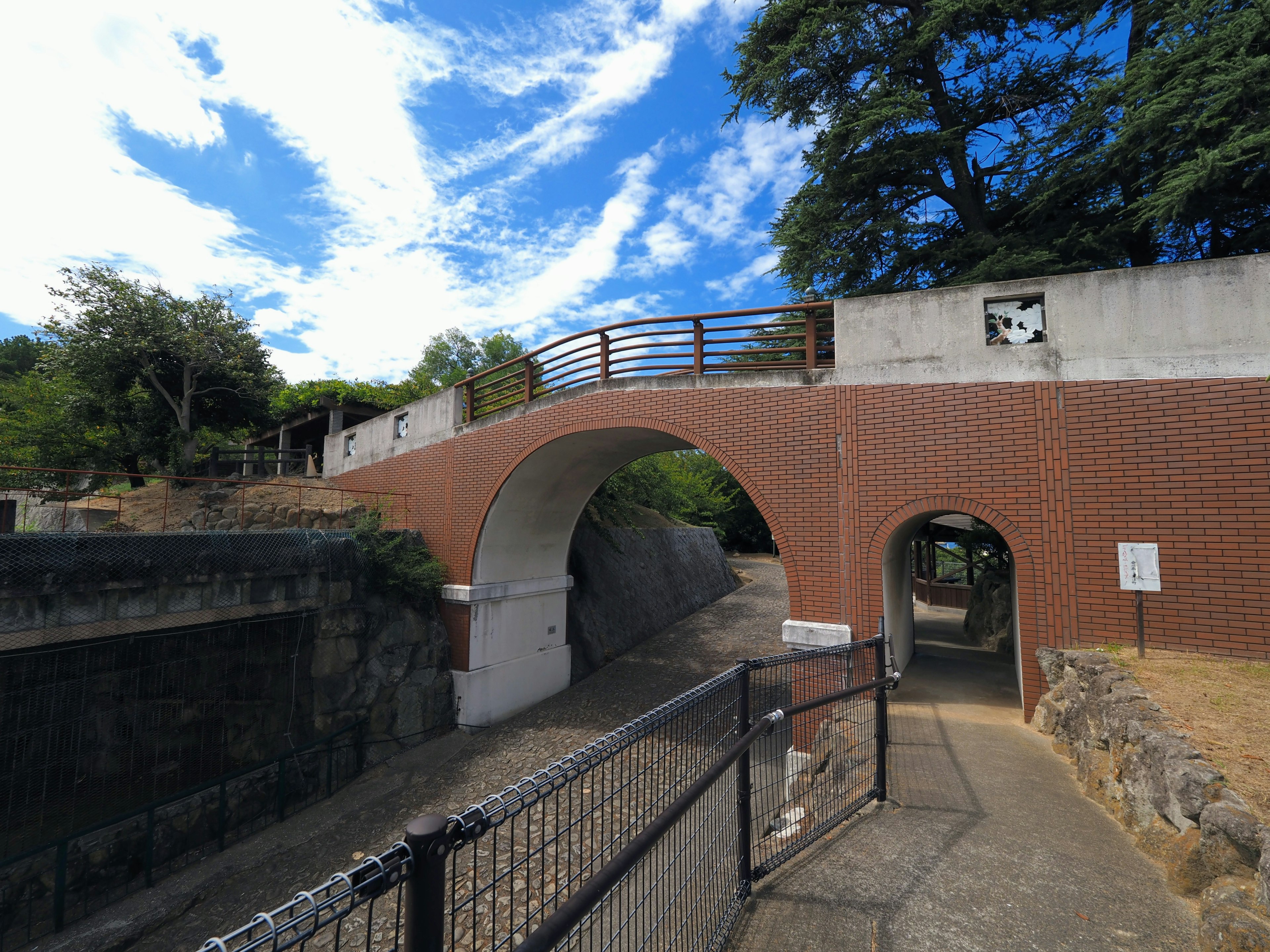 Puente de arco en un parque con cielo azul y árboles