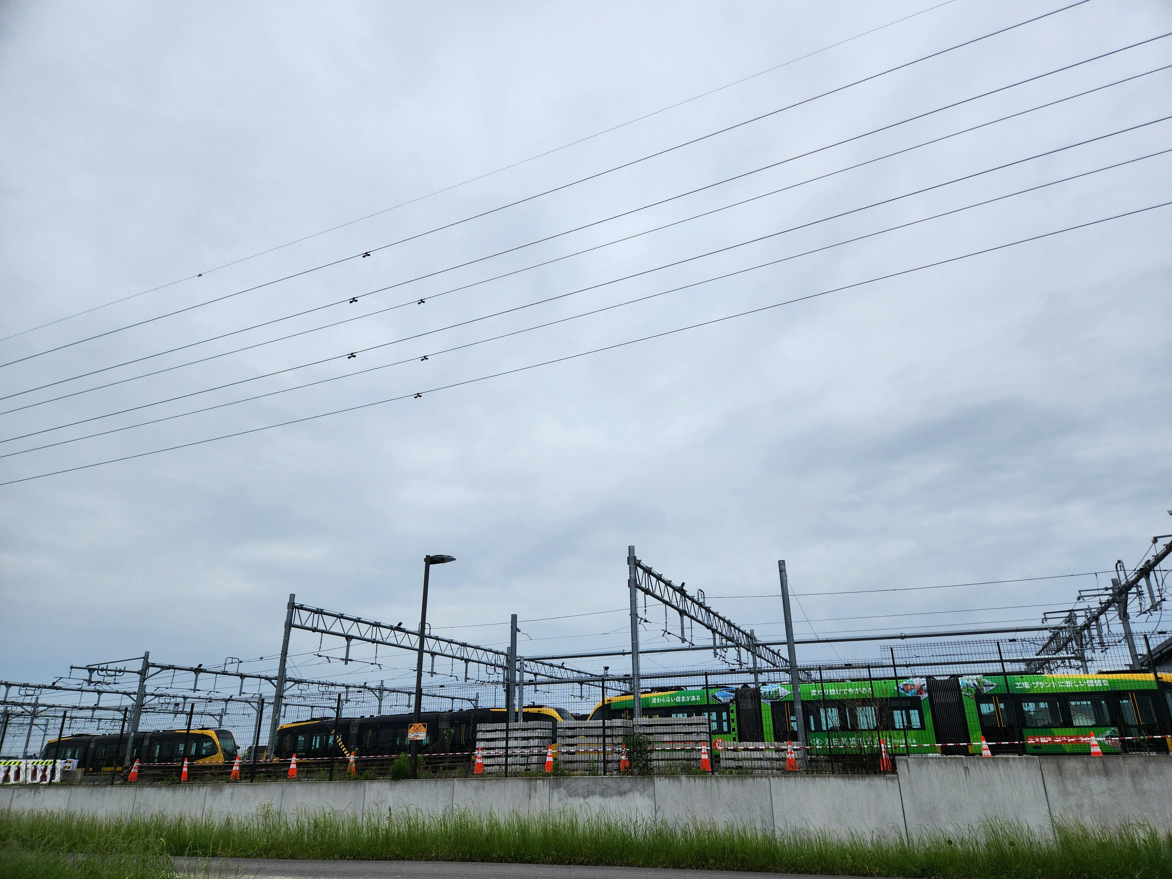 Railway tracks with green trains under a cloudy sky