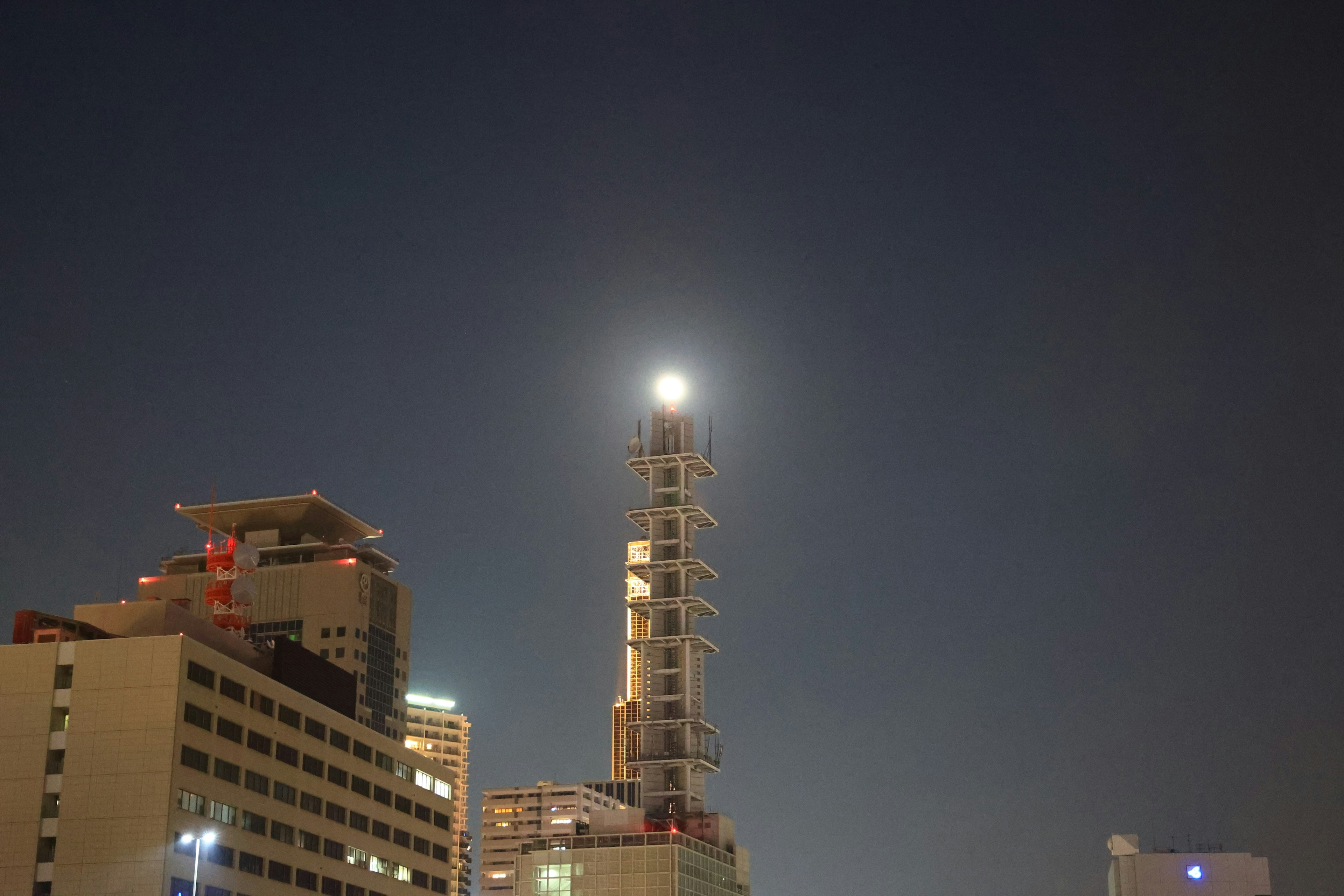 夜空に輝くタワーの上に満月が浮かぶ