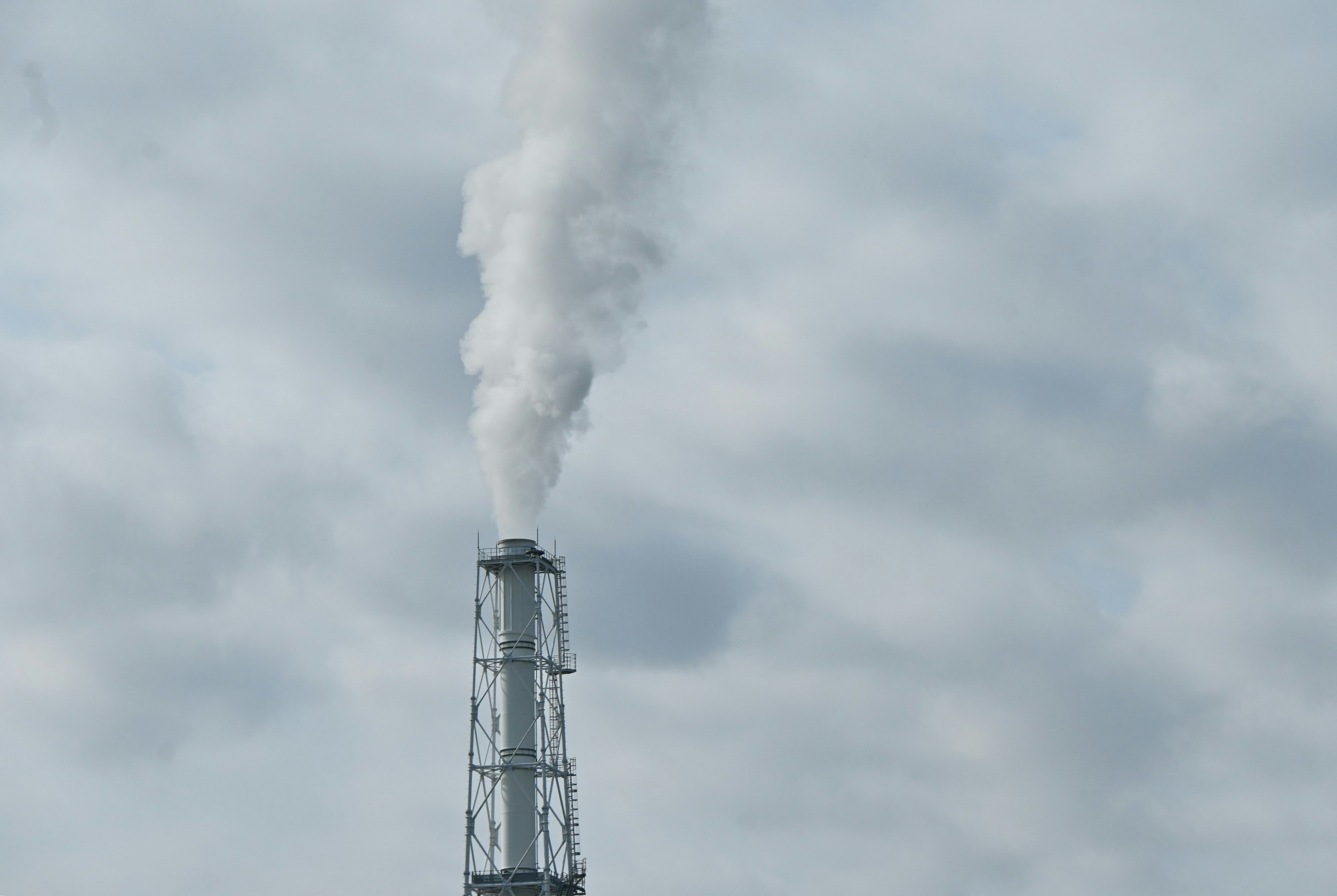 Smoke emitting chimney against a cloudy sky