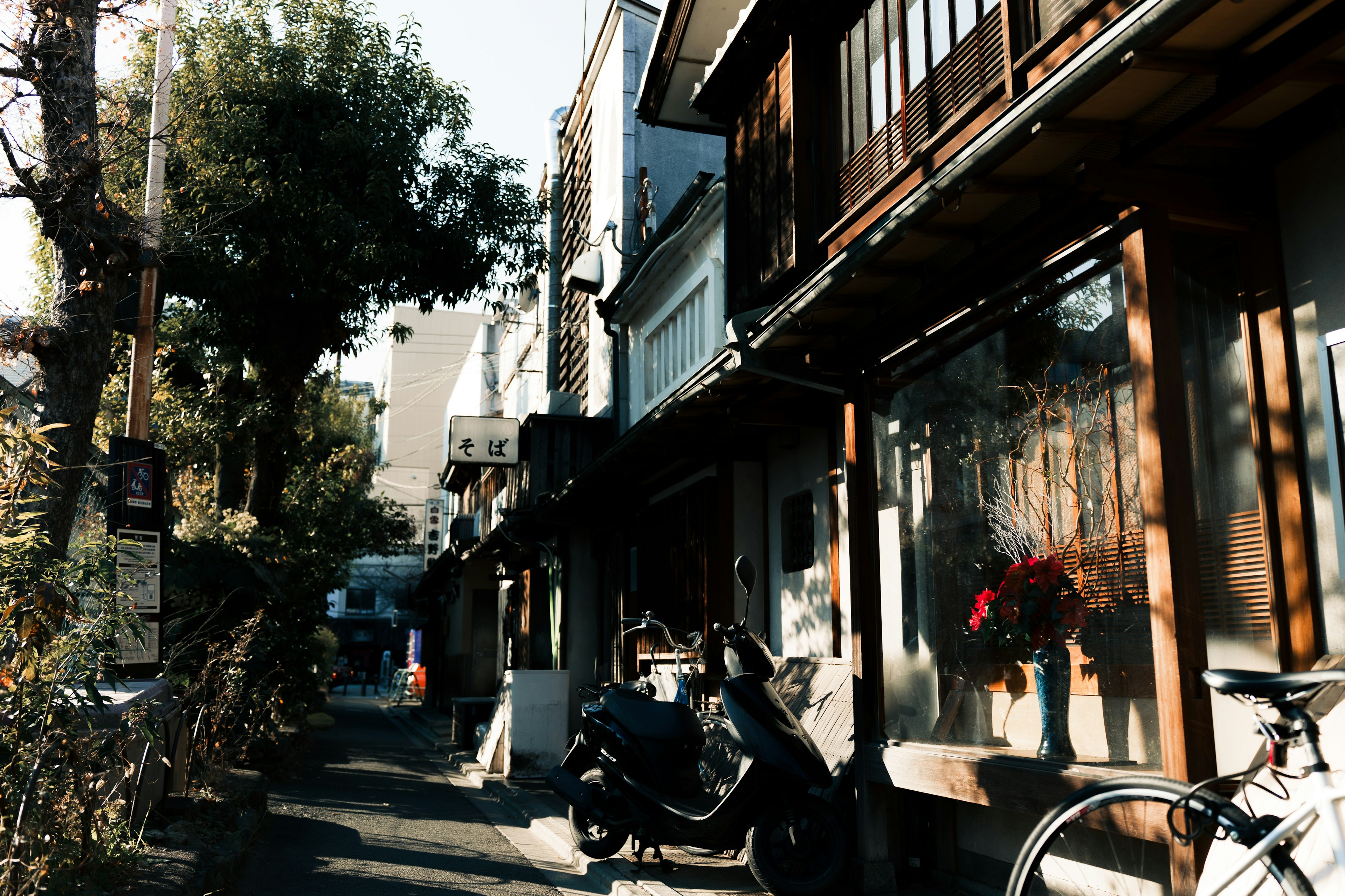 Narrow alley with traditional houses and parked scooters and bicycles