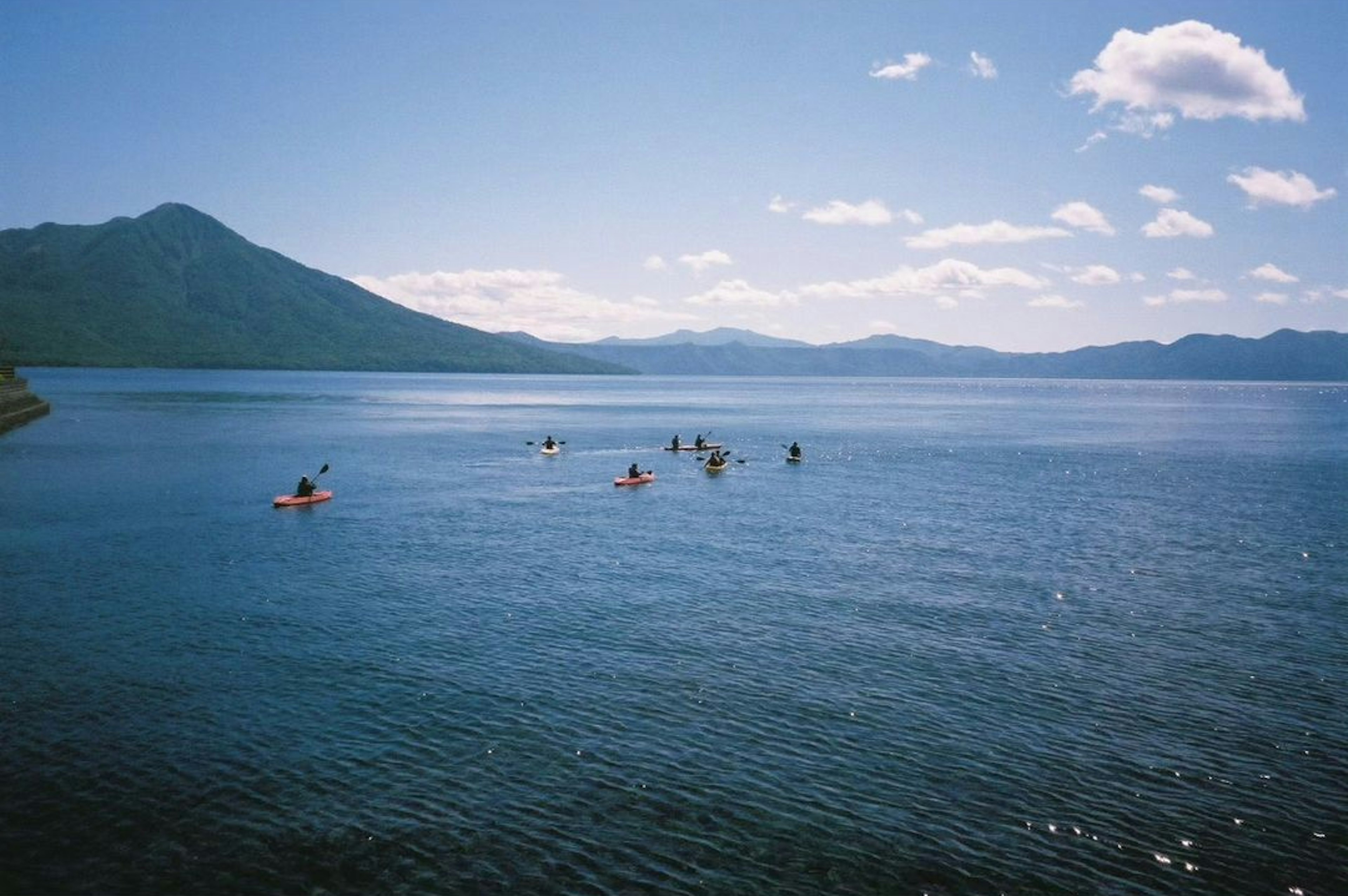 青い湖でカヤックを漕ぐ人々と山々の美しい風景