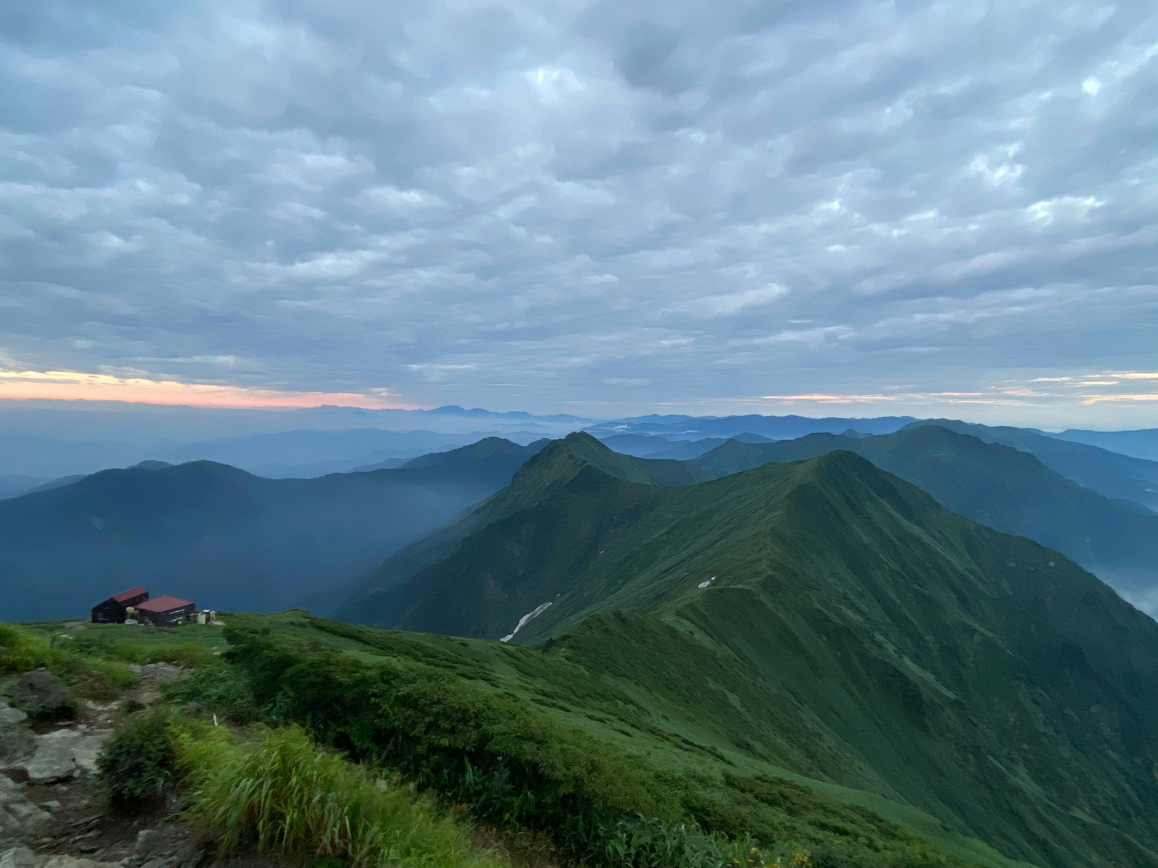 緑豊かな山々と雲の多い空が広がる風景