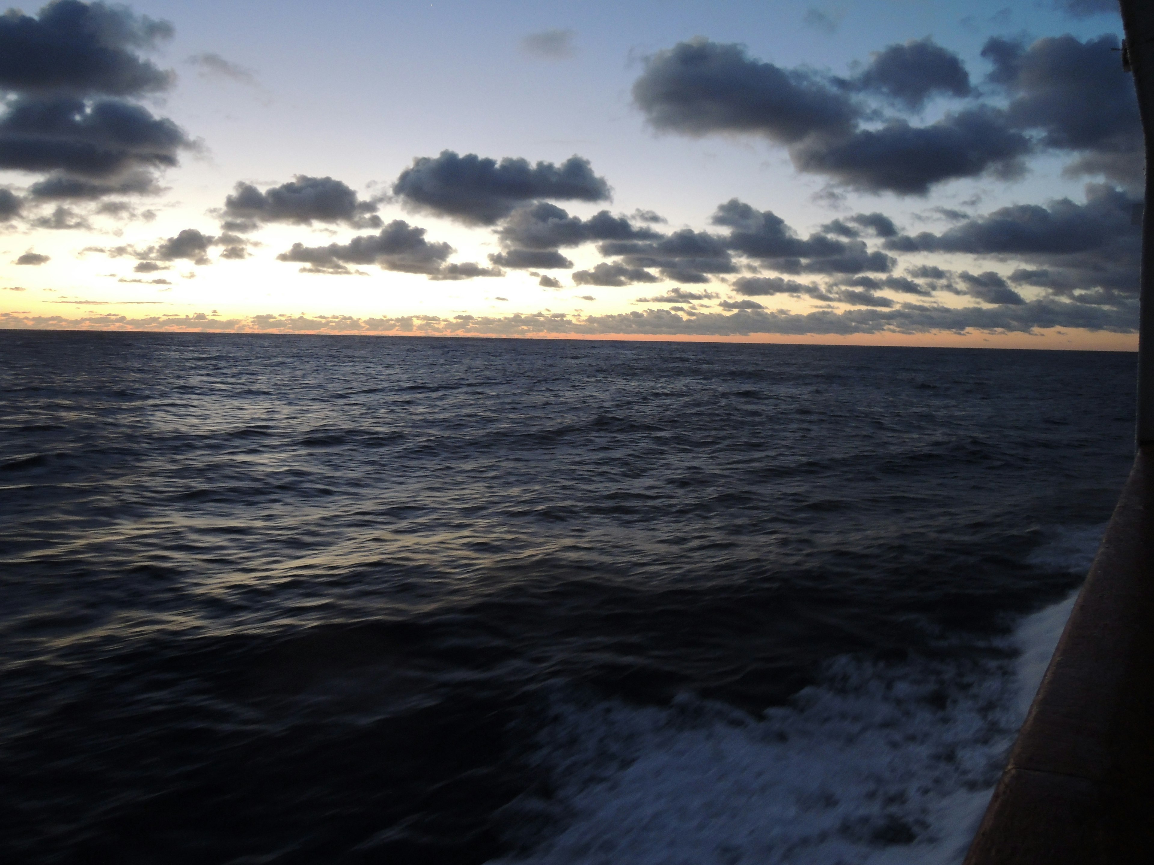 Pemandangan laut saat matahari terbenam dengan awan di langit