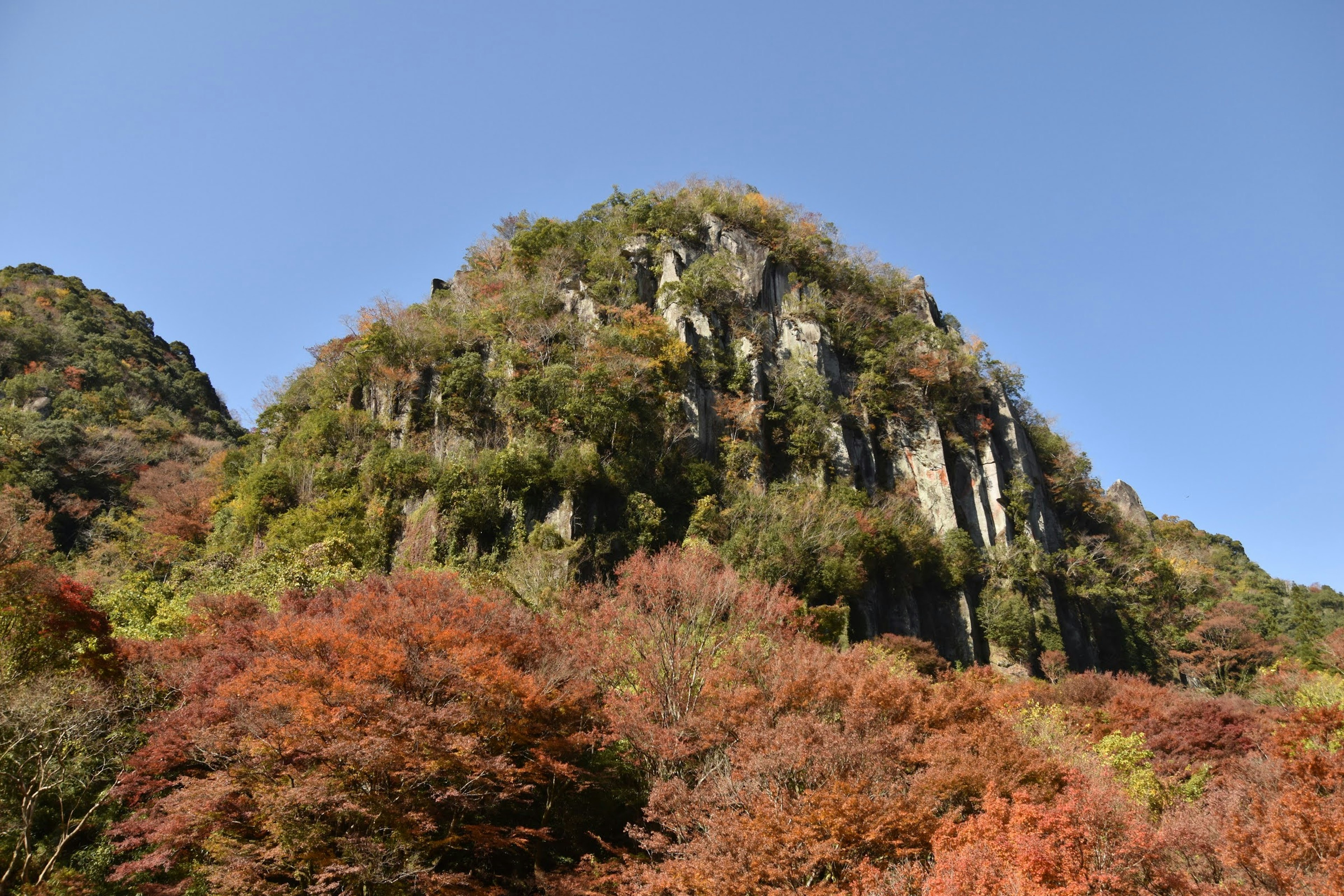 高山的風景，周圍環繞著五彩斑斕的秋天樹葉