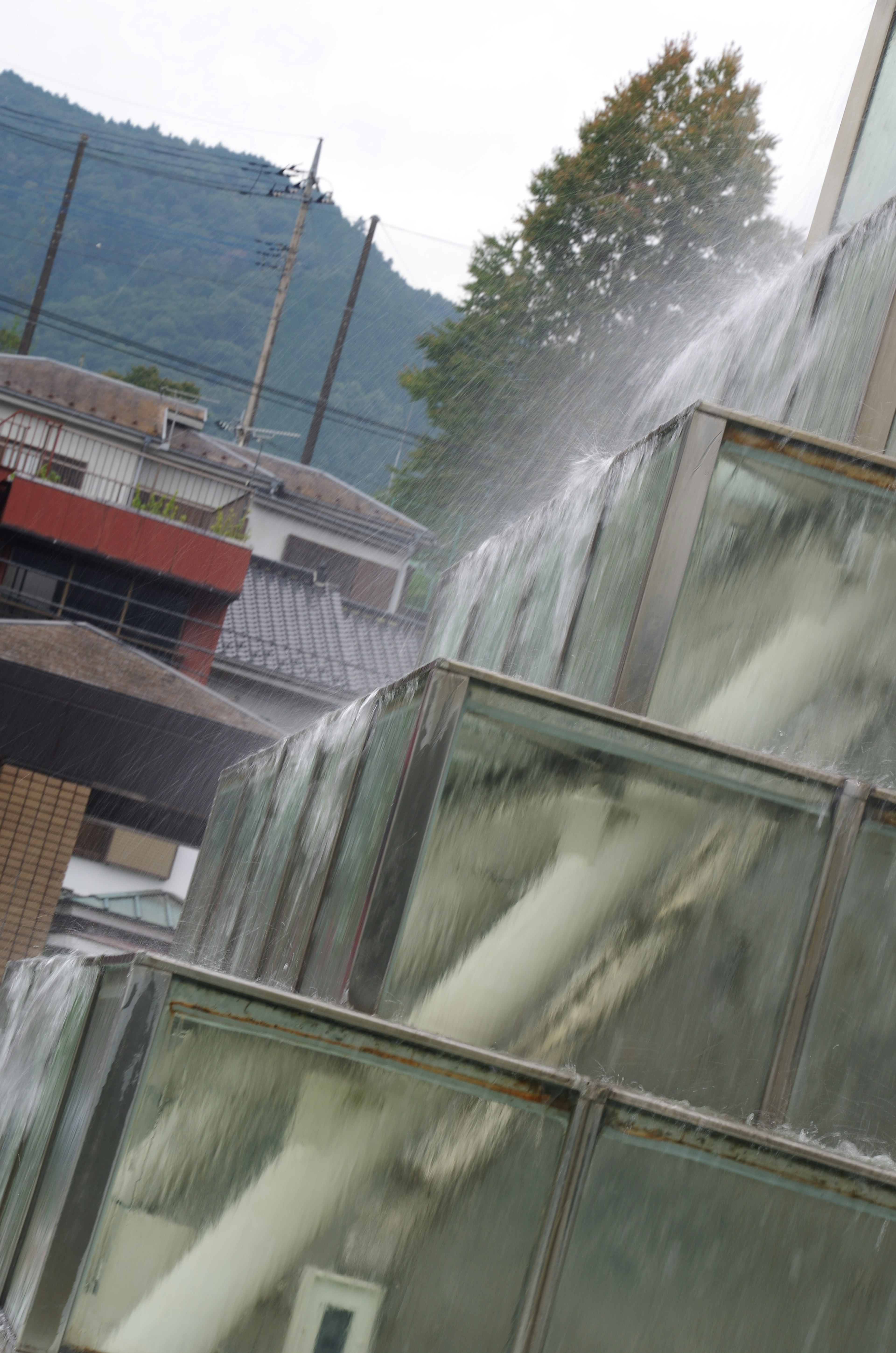 透明なガラスの階段状の噴水に流れる水と背景の山