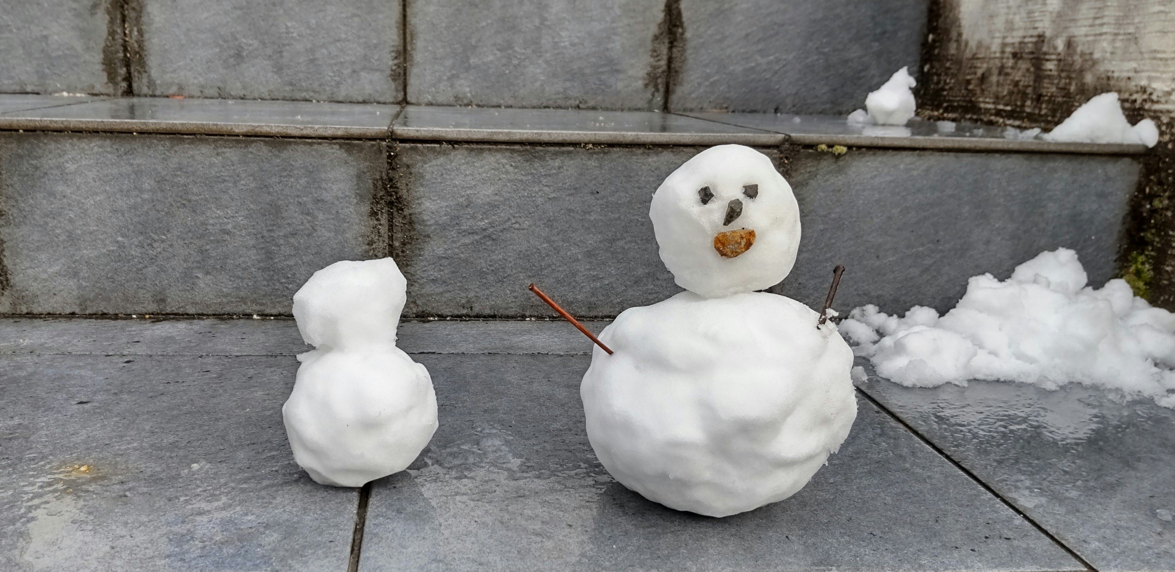 A snowman and a small snowball placed on a staircase