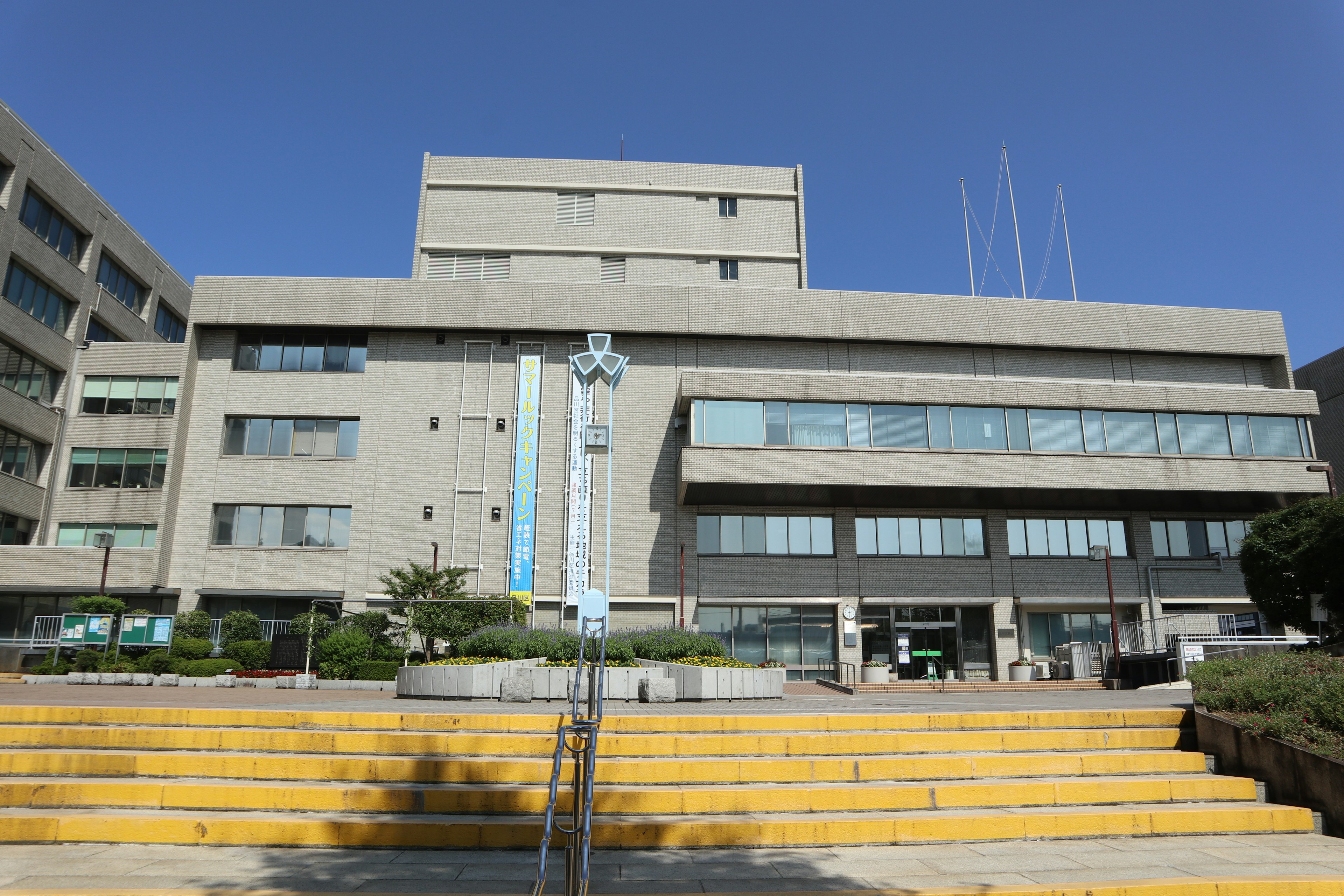 Edificio de concreto bajo un cielo azul con escaleras en primer plano