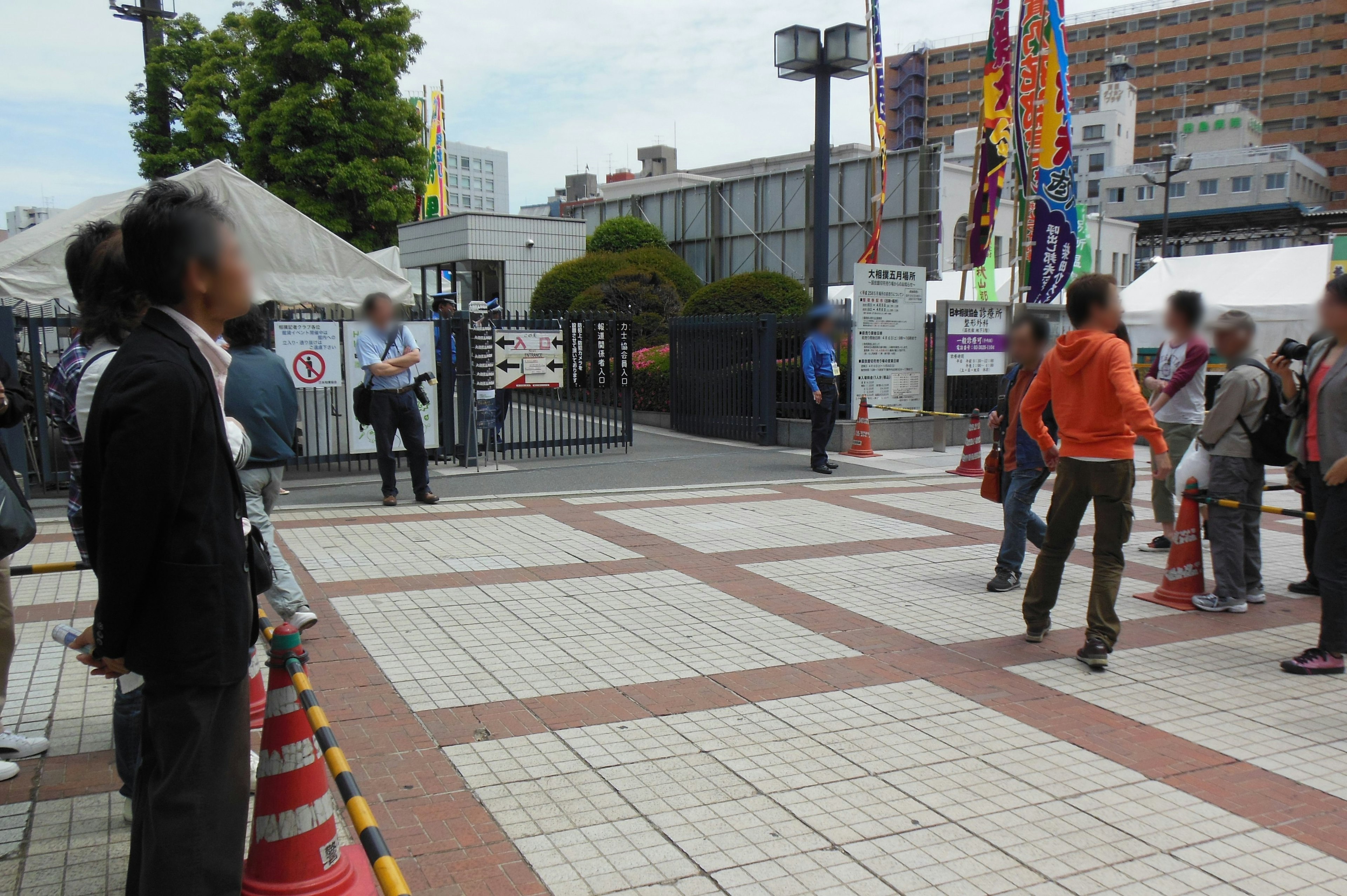 People walking at an intersection with surrounding buildings and traffic cones