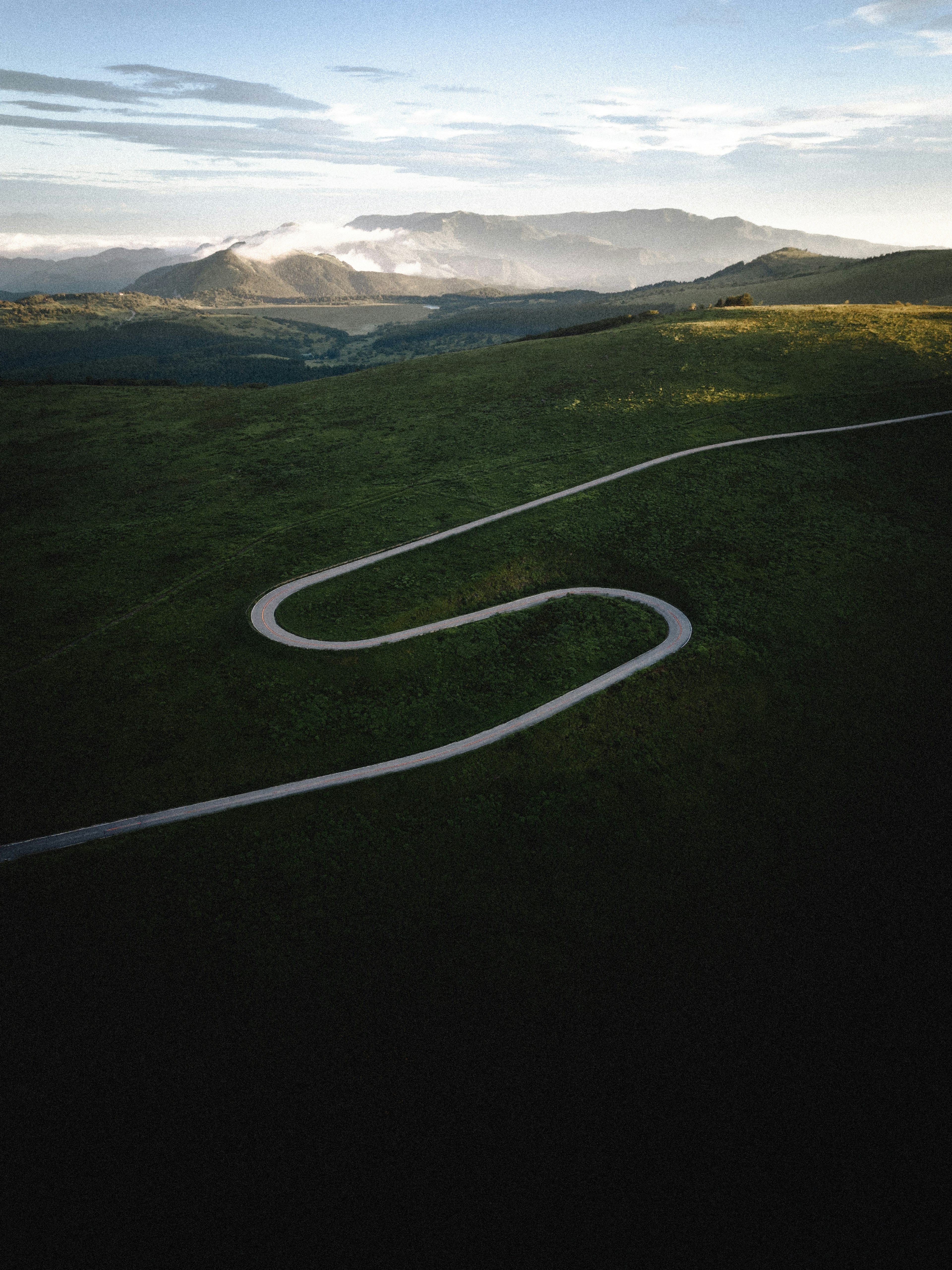 Winding road through green hills with distant mountains