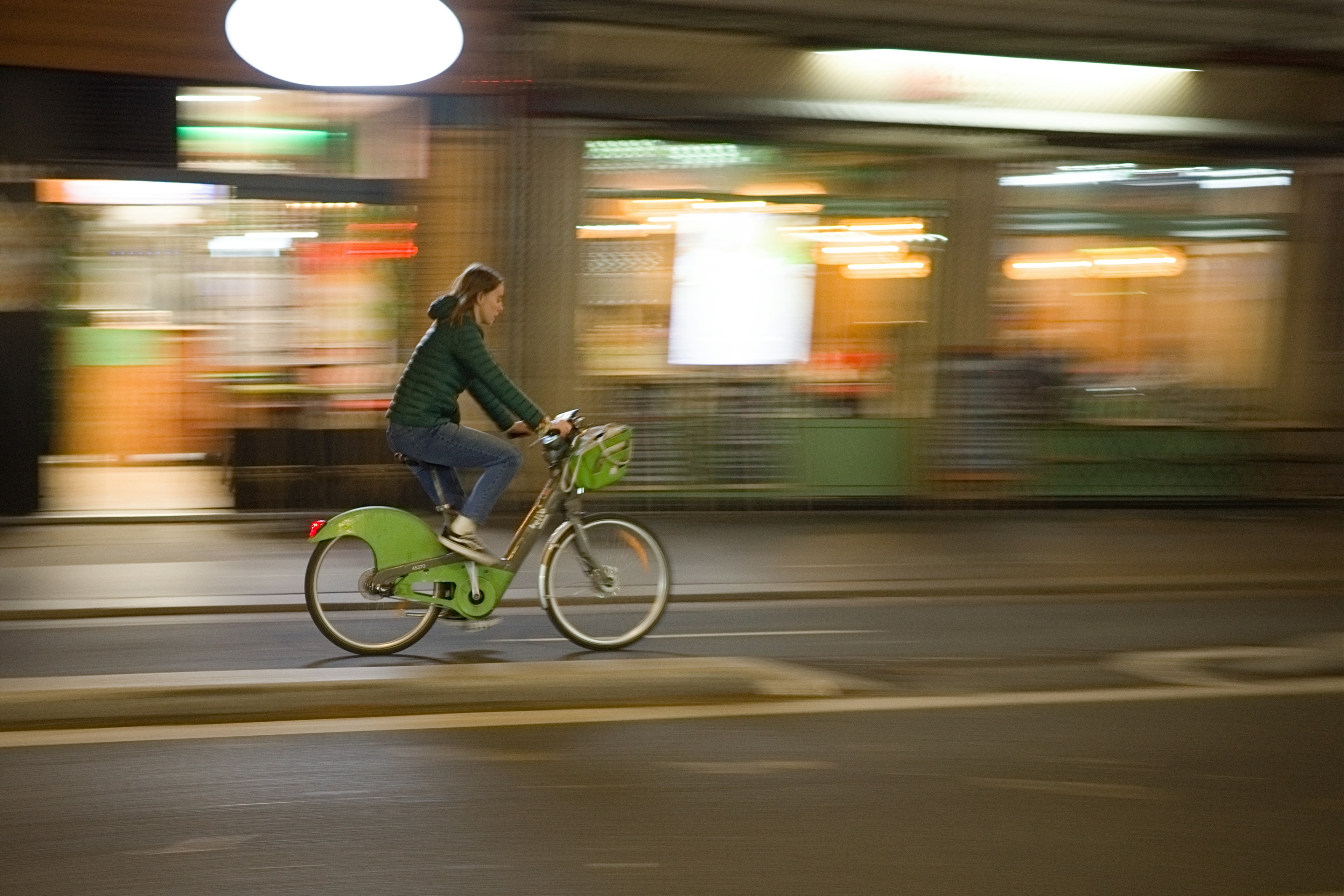 Une personne chevauchant un vélo vert dans une rue de la ville la nuit